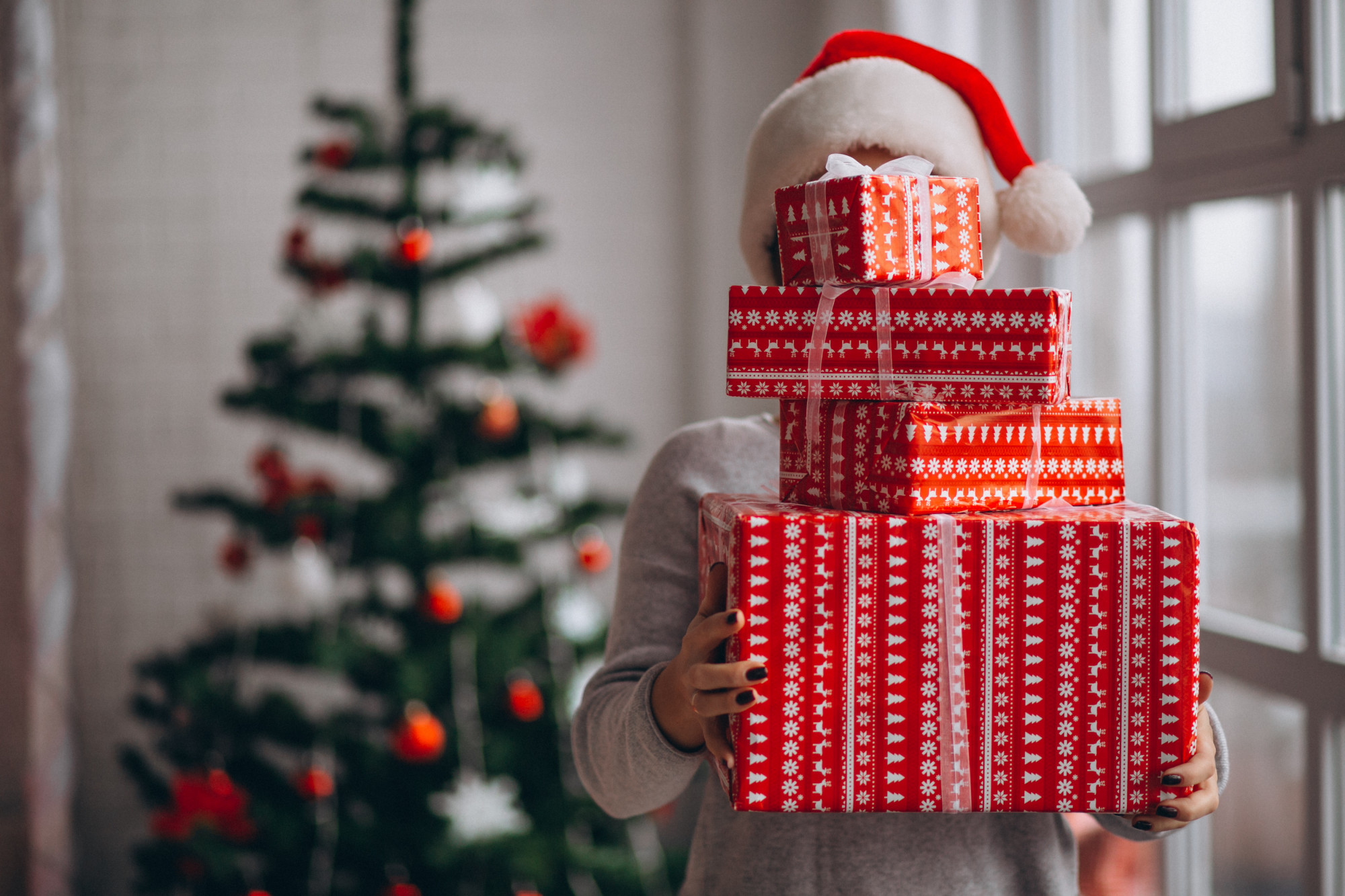 A woman holding a stack of Christmas presents | Source: Freepik