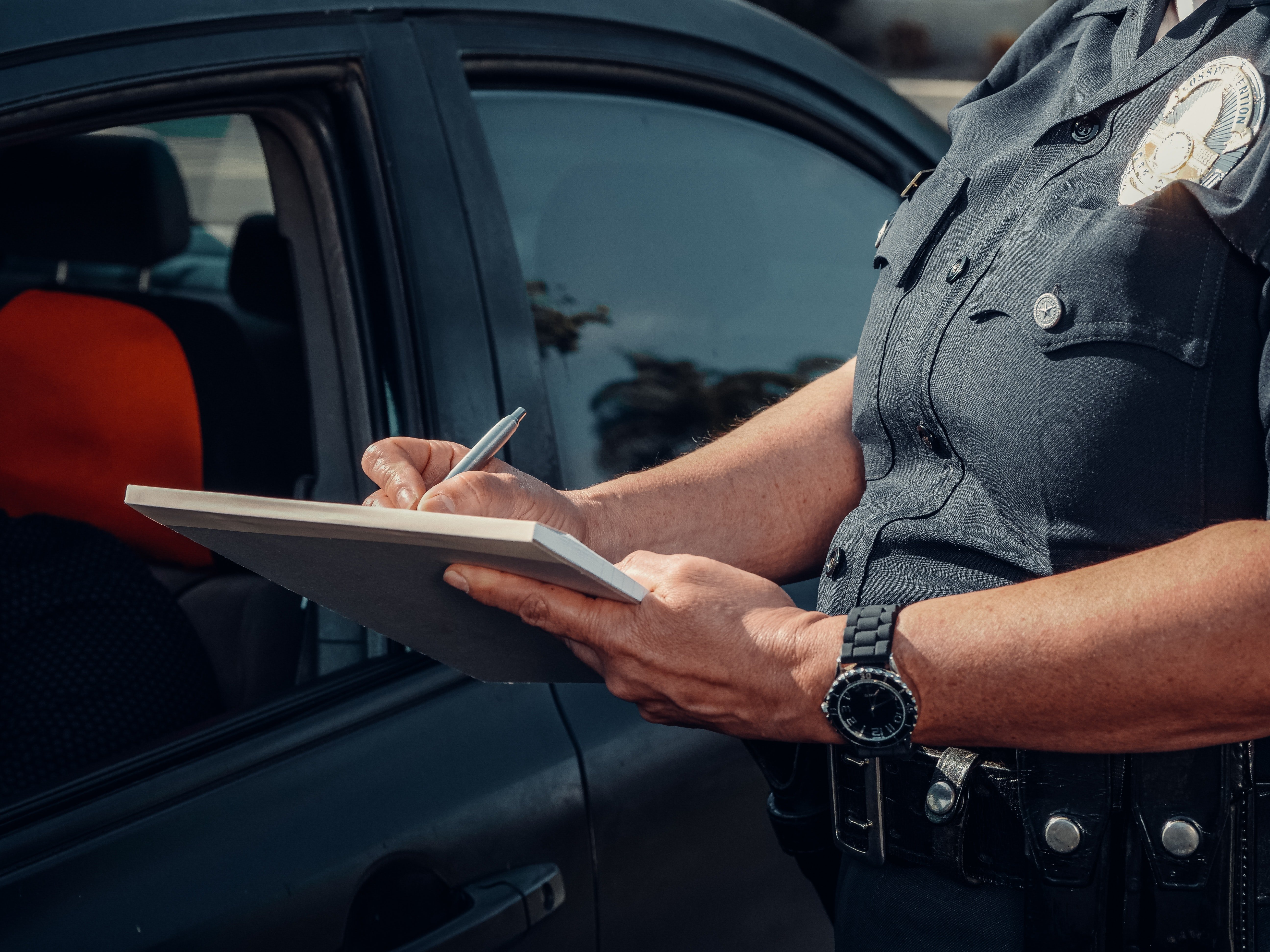 A police officer brings a driver to book and writes them a fine | Photo: Pexels/Kindel Media
