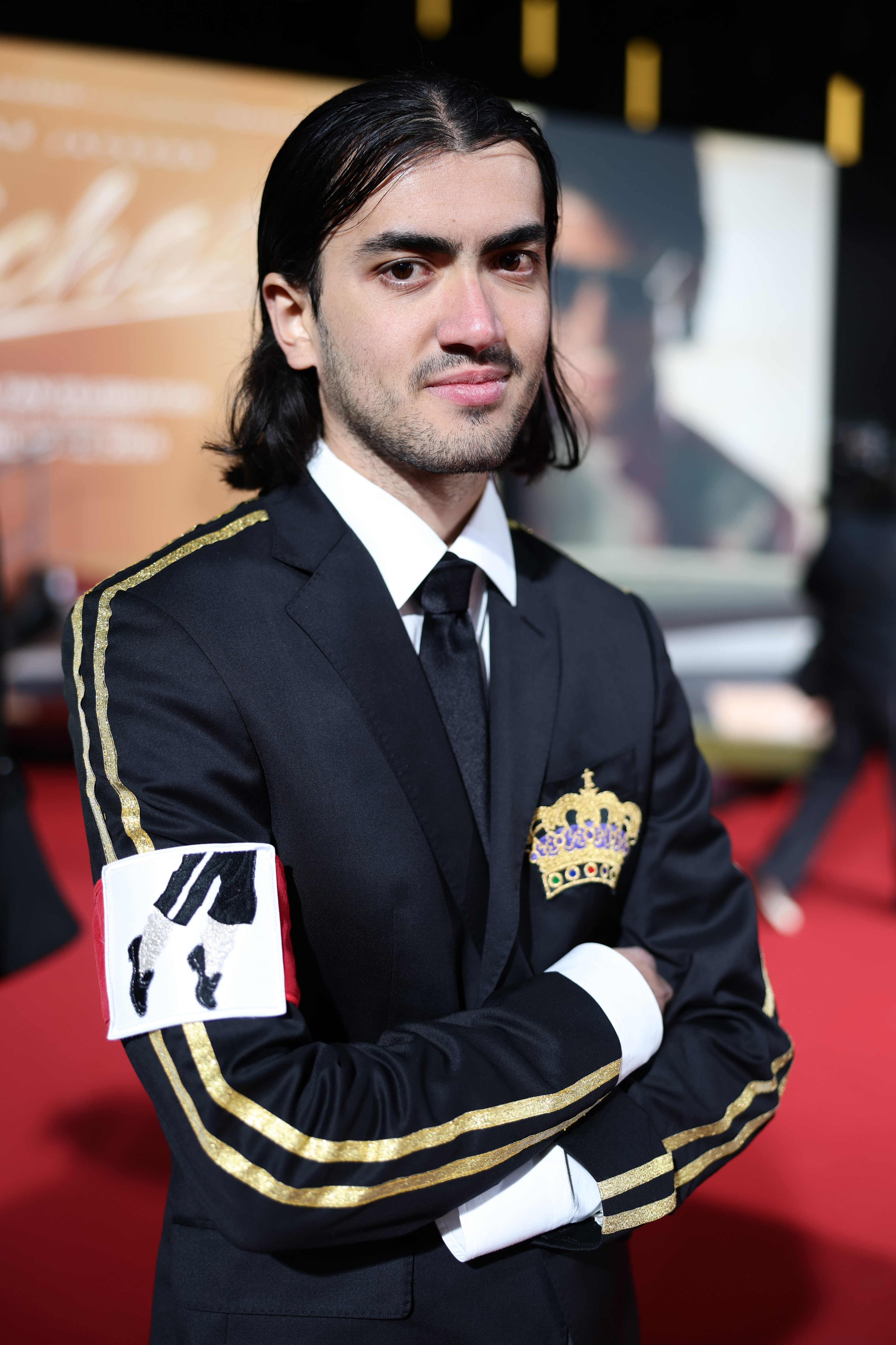 Bigi Jackson wears a suit jacket featuring an armband with a photo of Michael Jackson's feet in an iconic dance move during the "Michael" premiere at Uber Eats Music Hall on April 10, 2026, in Berlin, Germany.