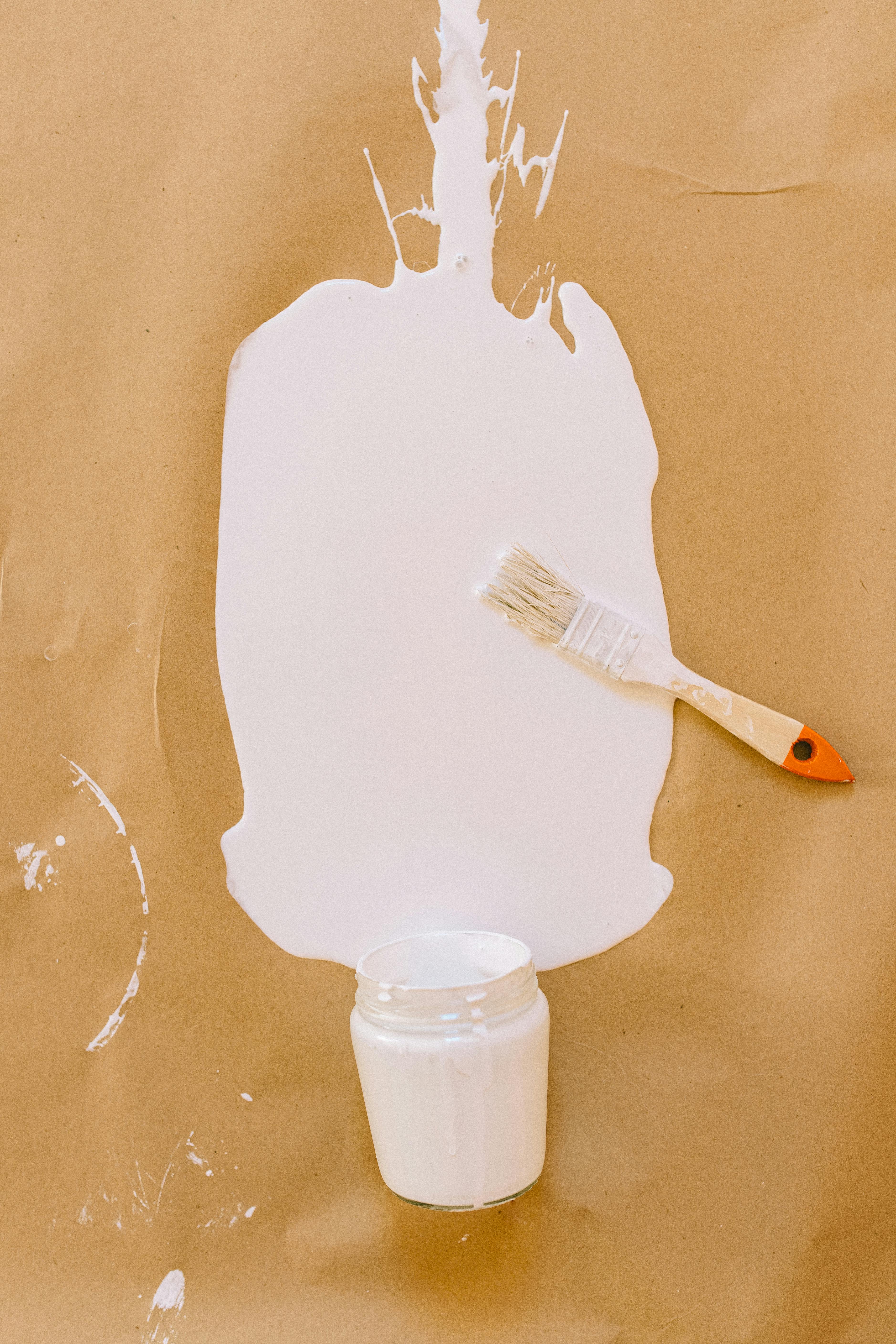 White paint and brush on brown paper | Source: Pexels