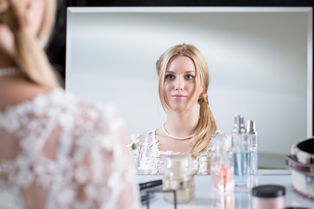 Une femme mécontente de sa coiffure devant son miroir. | Photo : Shutterstock