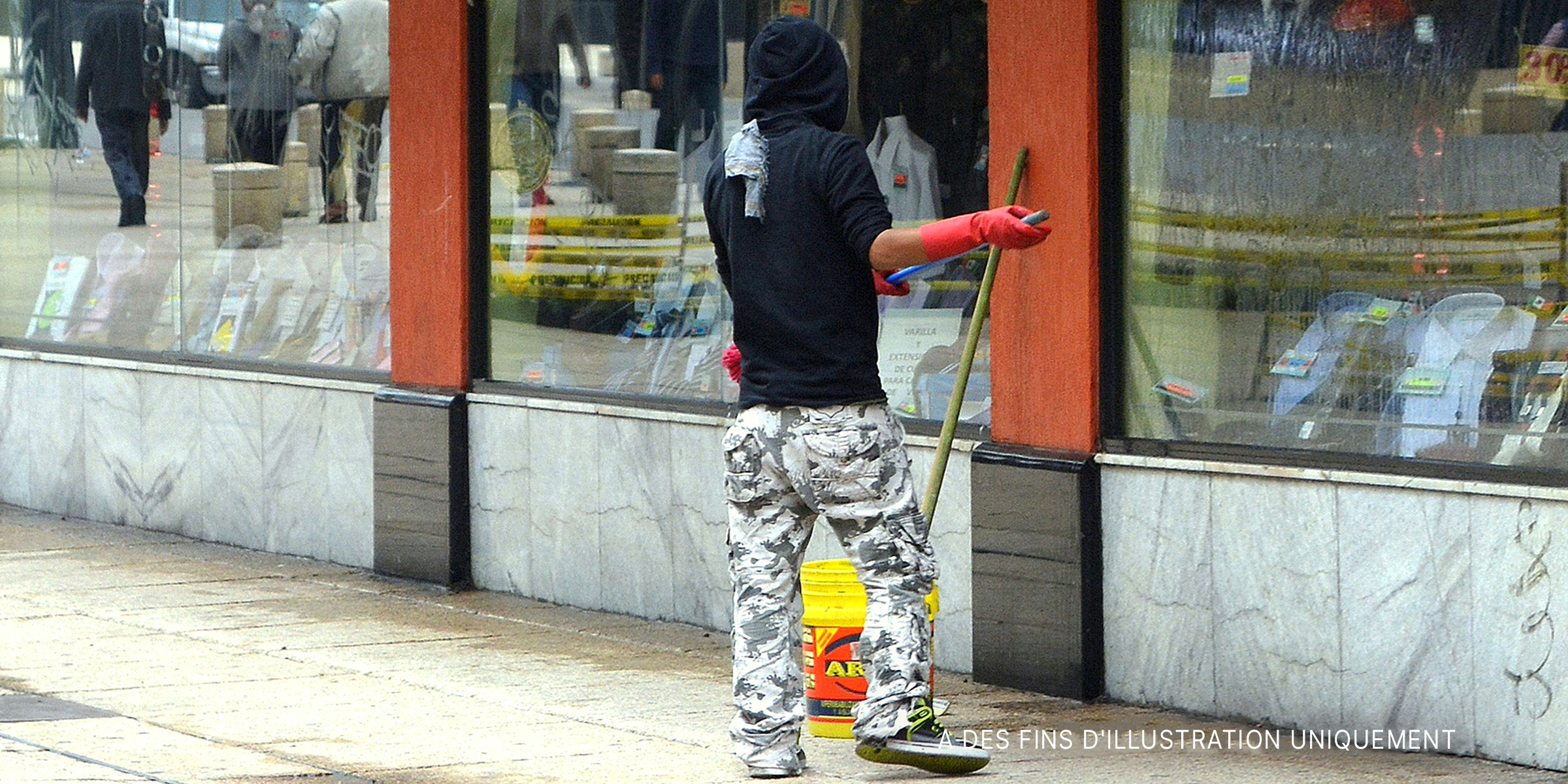 Un homme balayant le trottoir à l'extérieur d'un magasin. | Source : Flickr / Carl Campbell (CC BY-SA 2.0)