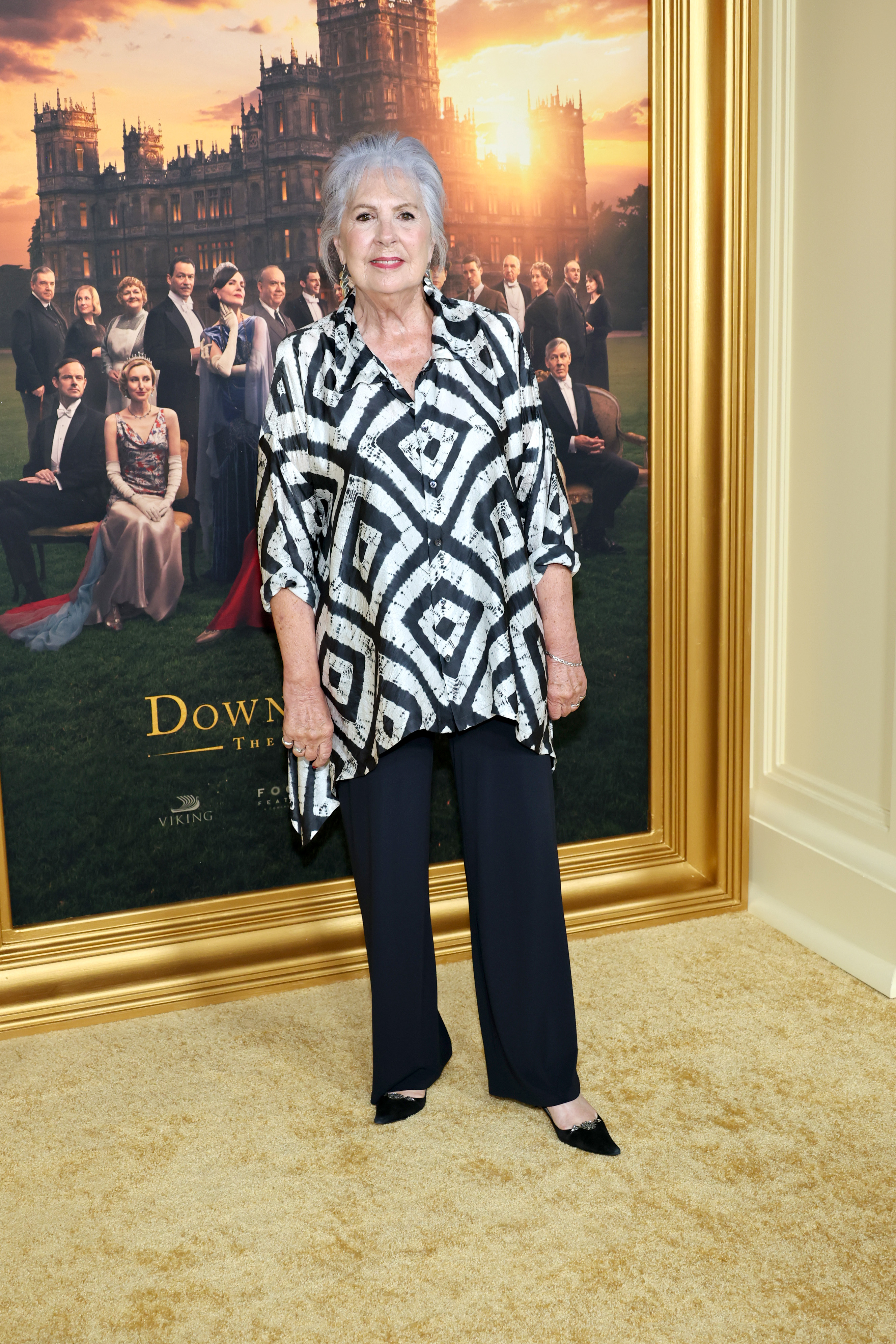 At the 2025 New York premiere of "Downton Abbey: The Grand Finale," Wilton embraced bold patterns in a black-and-white printed blouse paired with flowing trousers. With her silver hair elegantly styled and her signature grace intact, she proved that timeless elegance only deepens with age.