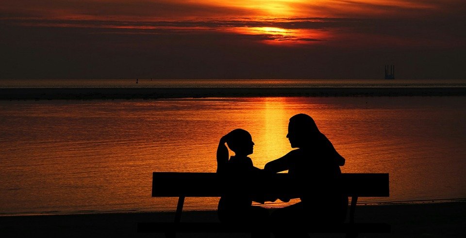 A mother and daughter discussing against the background of the sun setting. | Photo: Pixabay