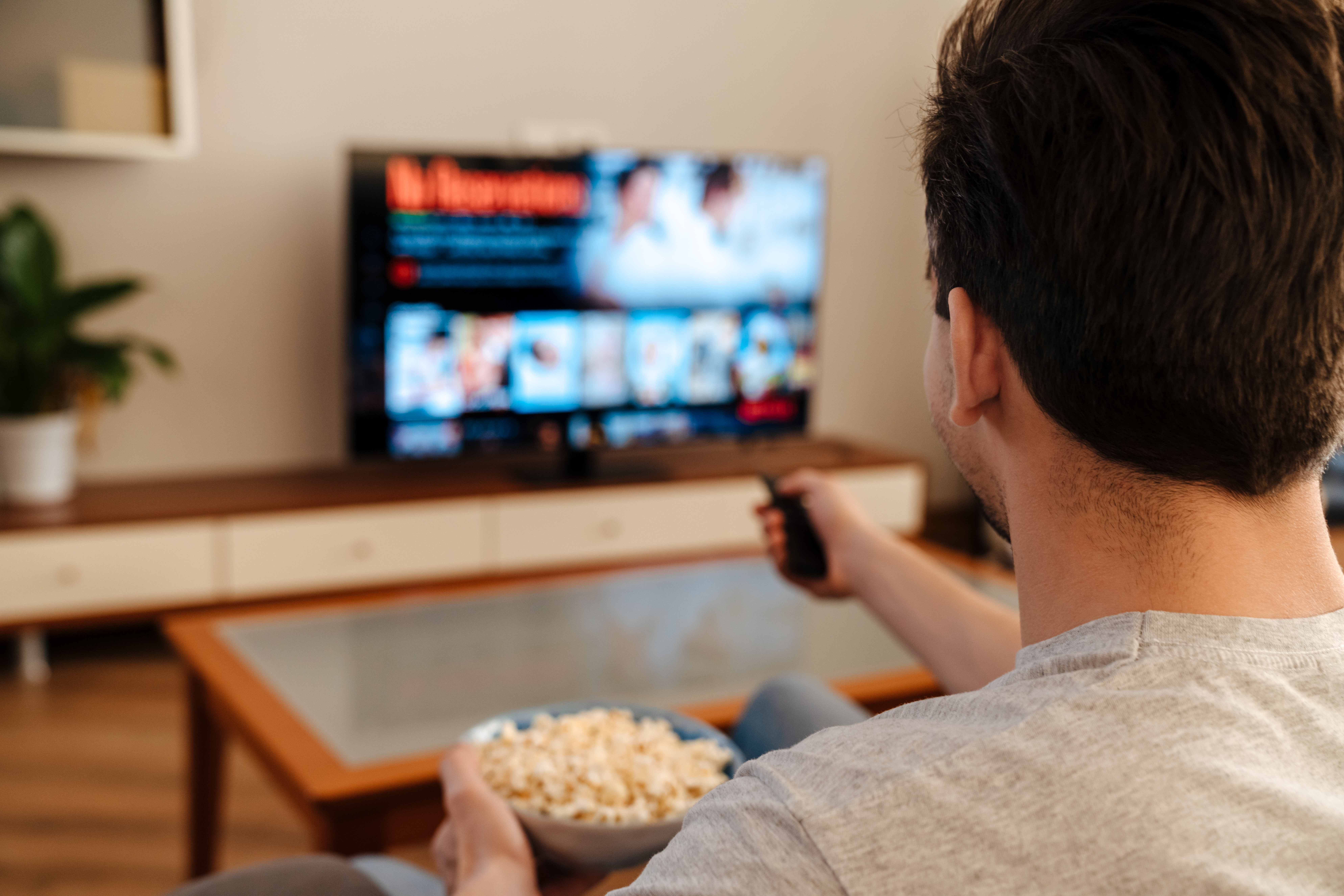 A man watching TV and eating popcorn at home | Source: Shutterstock