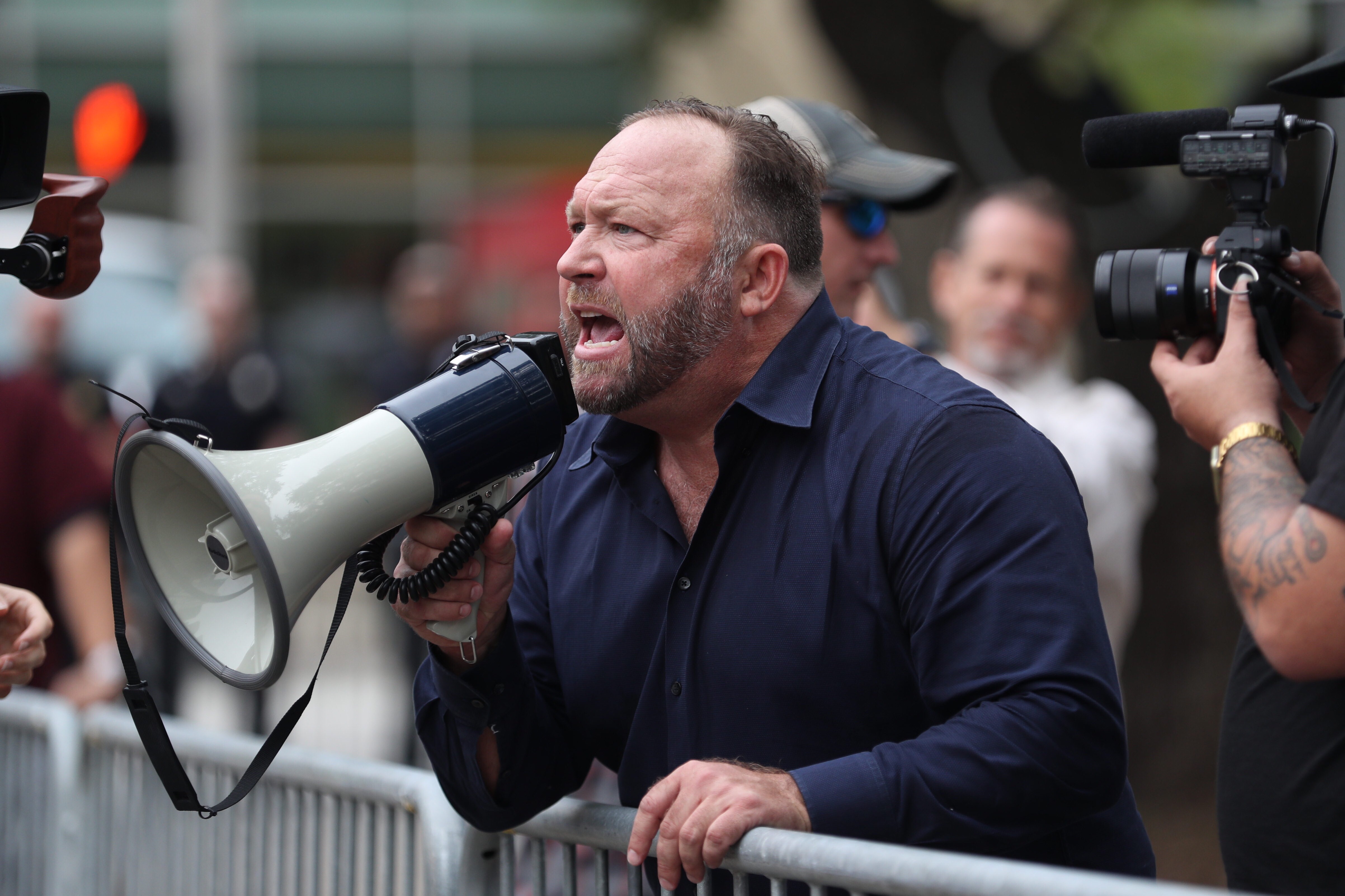 Alex Jones yells at protestors outside of Toyota Center before a Trump campaign rally on October 22, 2018, in Houston, Texas. | Sources: Getty Images