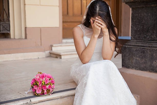 A broken bride sitting on a pavement while crying | Source: Pexels