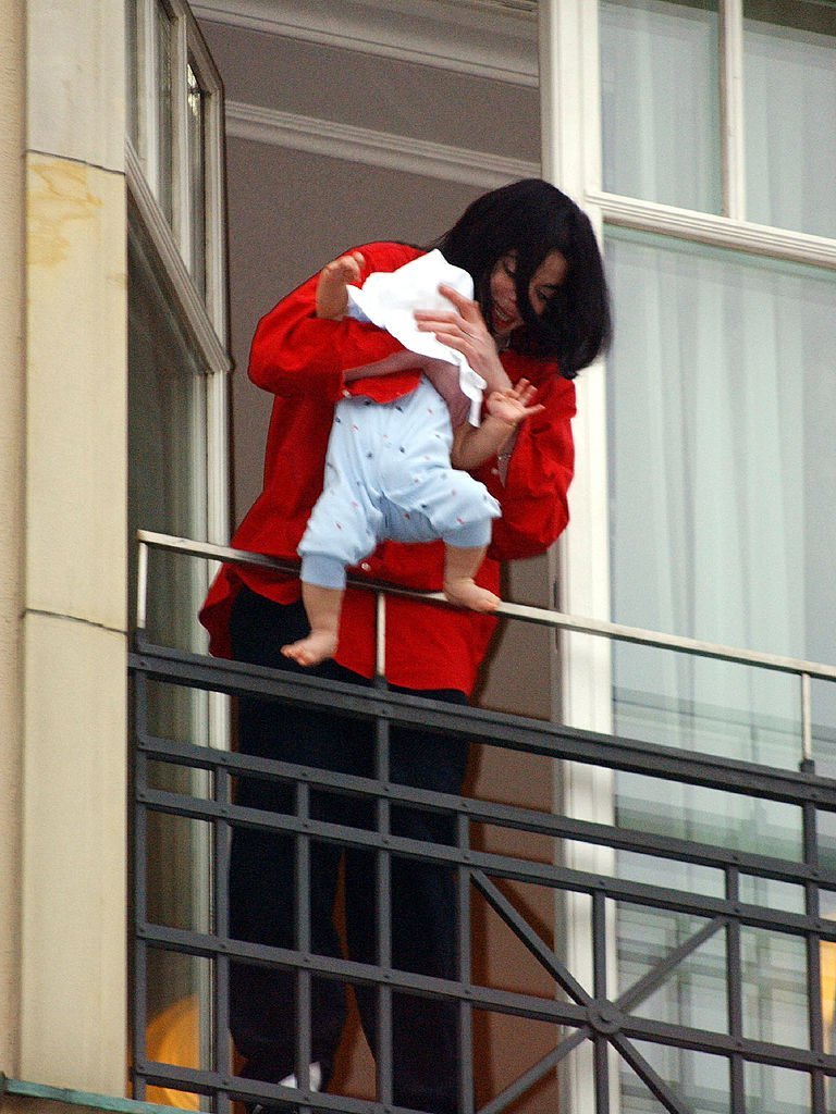 Michael Jackson baumelt im November 2002 den 9 Monate alten Blanket vom Balkon seines Hotels in Deutschland. | Quelle: Getty Images