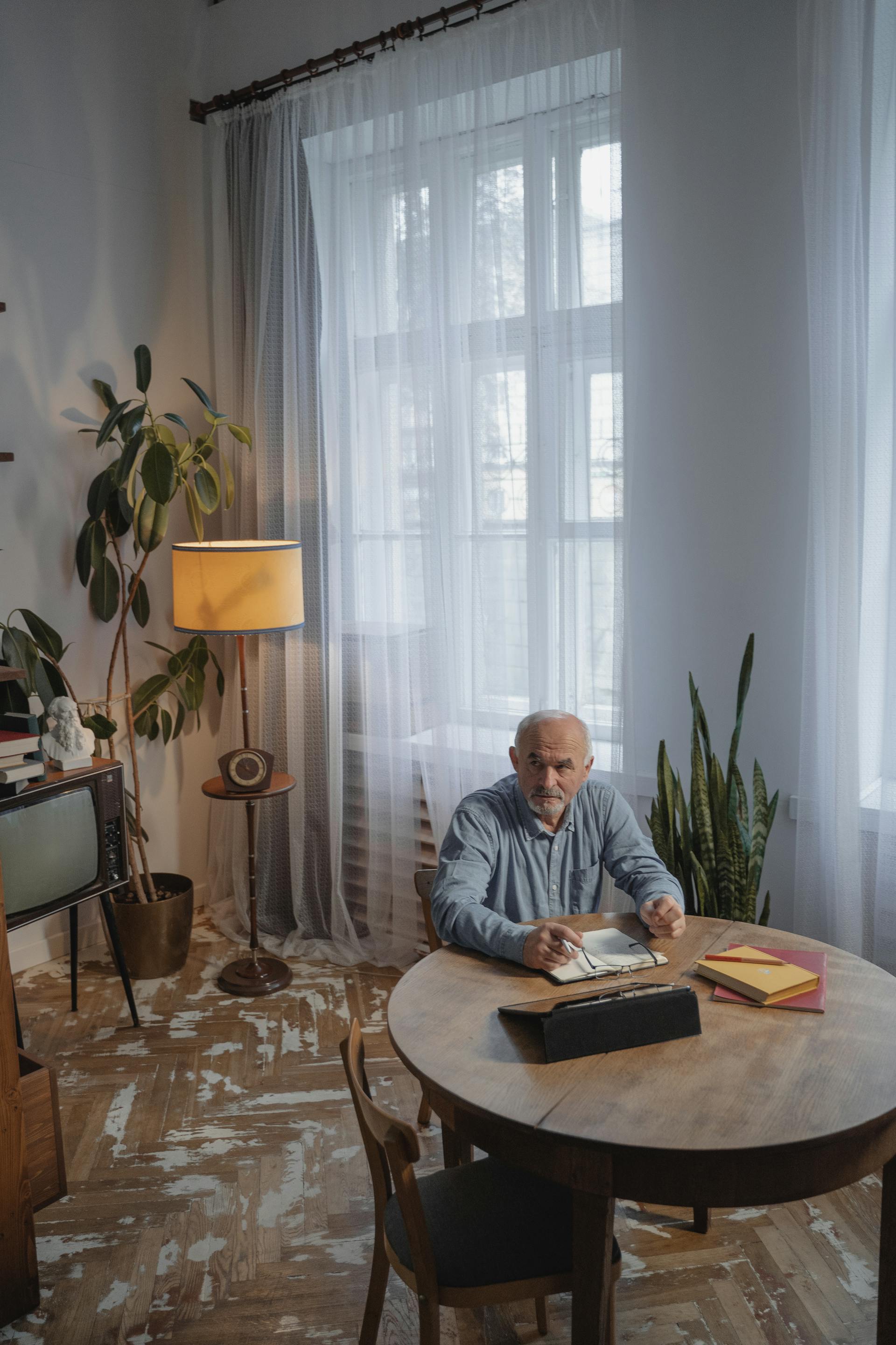 An older man seated on a brown wooden chair looking up | Source: Pexels