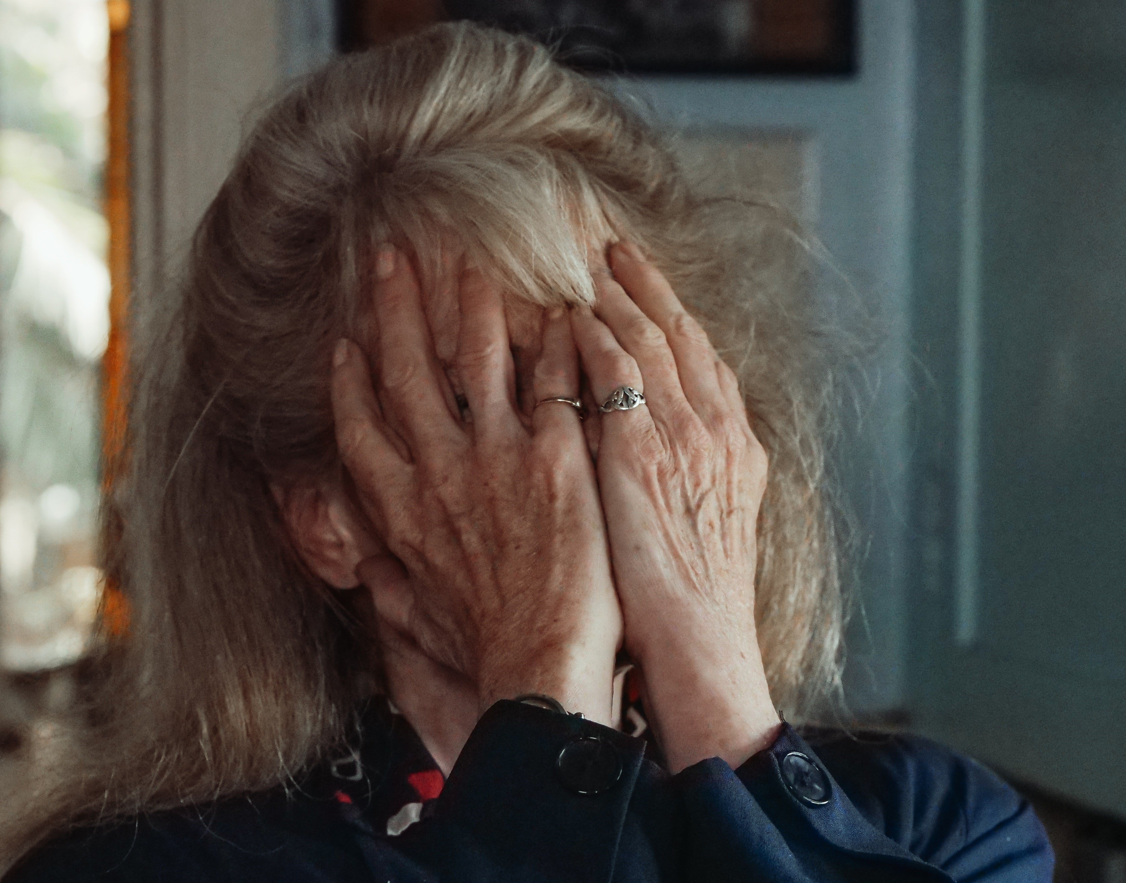 An upset elderly woman covering her face in distress | Source: Pexels