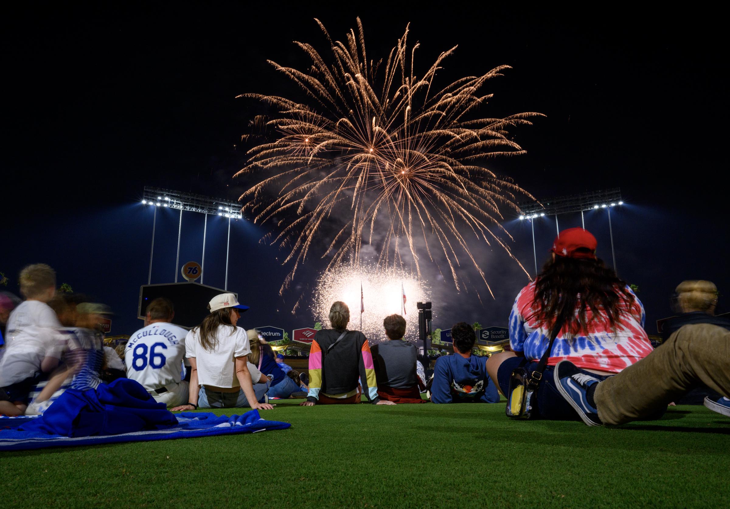 Fans and players sit on the infield to view the fireworks display over Dodger Stadium in Los Angeles, California, on July 4, 2024 | Source: Getty Images