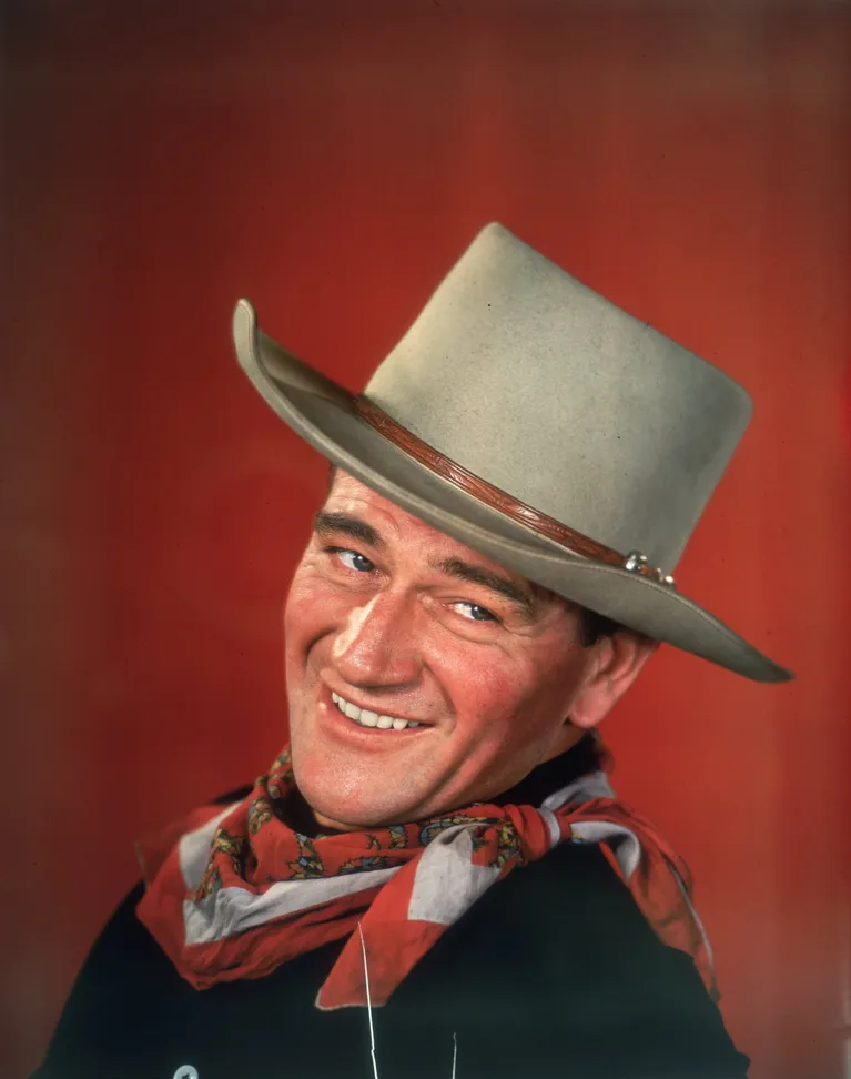 Ein Studioporträt von John Wayne in Westernkleidung, mit zur Seite gedrehtem Kopf, um 1955. | Quelle: Getty Images