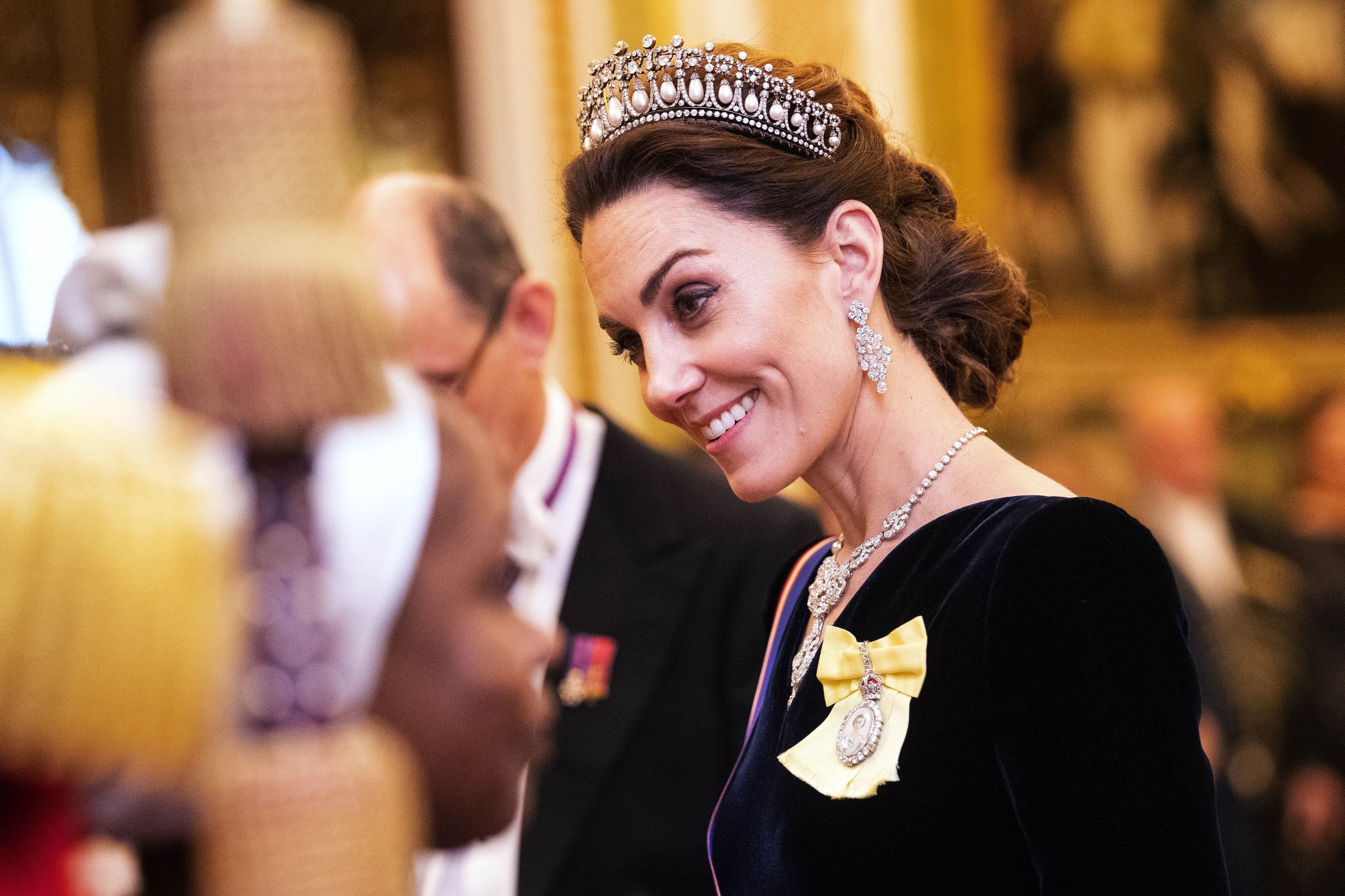 Kate Middleton talks to guests at an evening reception for members of the Diplomatic Corps at Buckingham Palace. | Source: Getty Images