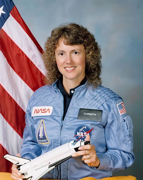 Portrait of Christa McAuliffe in NASA uniform with U.S. flag in the background | Source: Wikimedia Commons