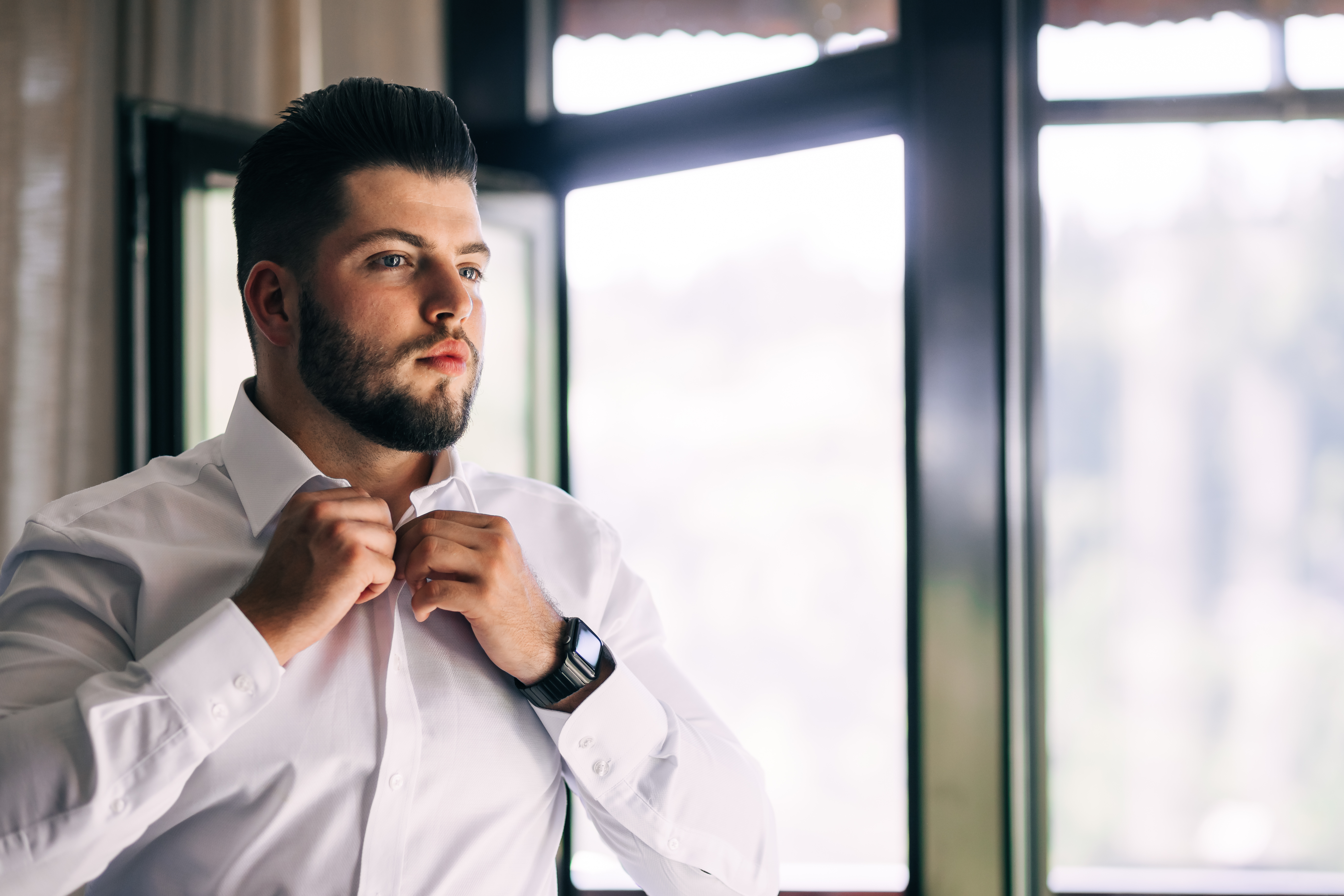 A man buttoning up his white suit shirt | Source: Shutterstock