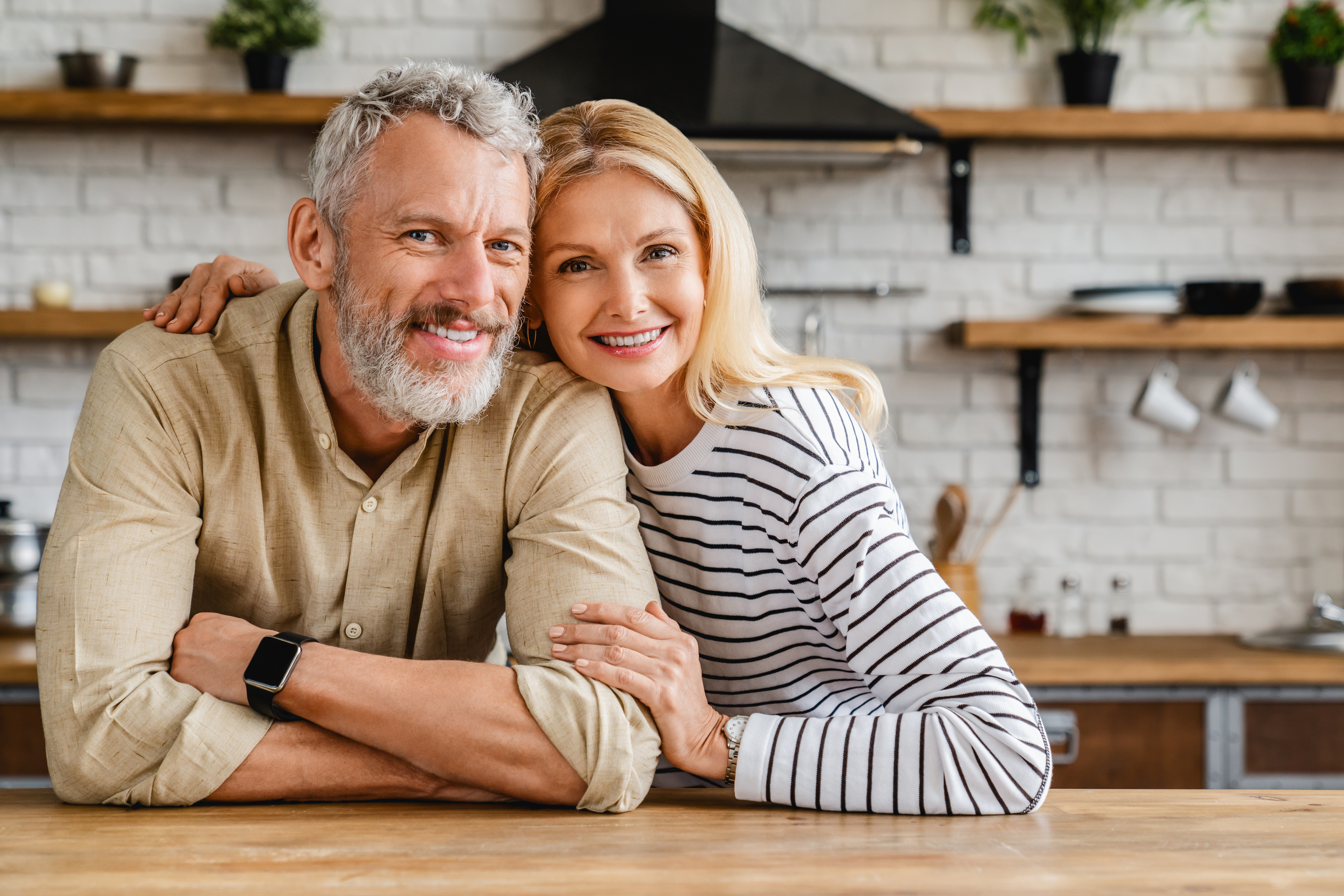 A middle-aged couple hugging in the kitchen | Source: Shutterstock