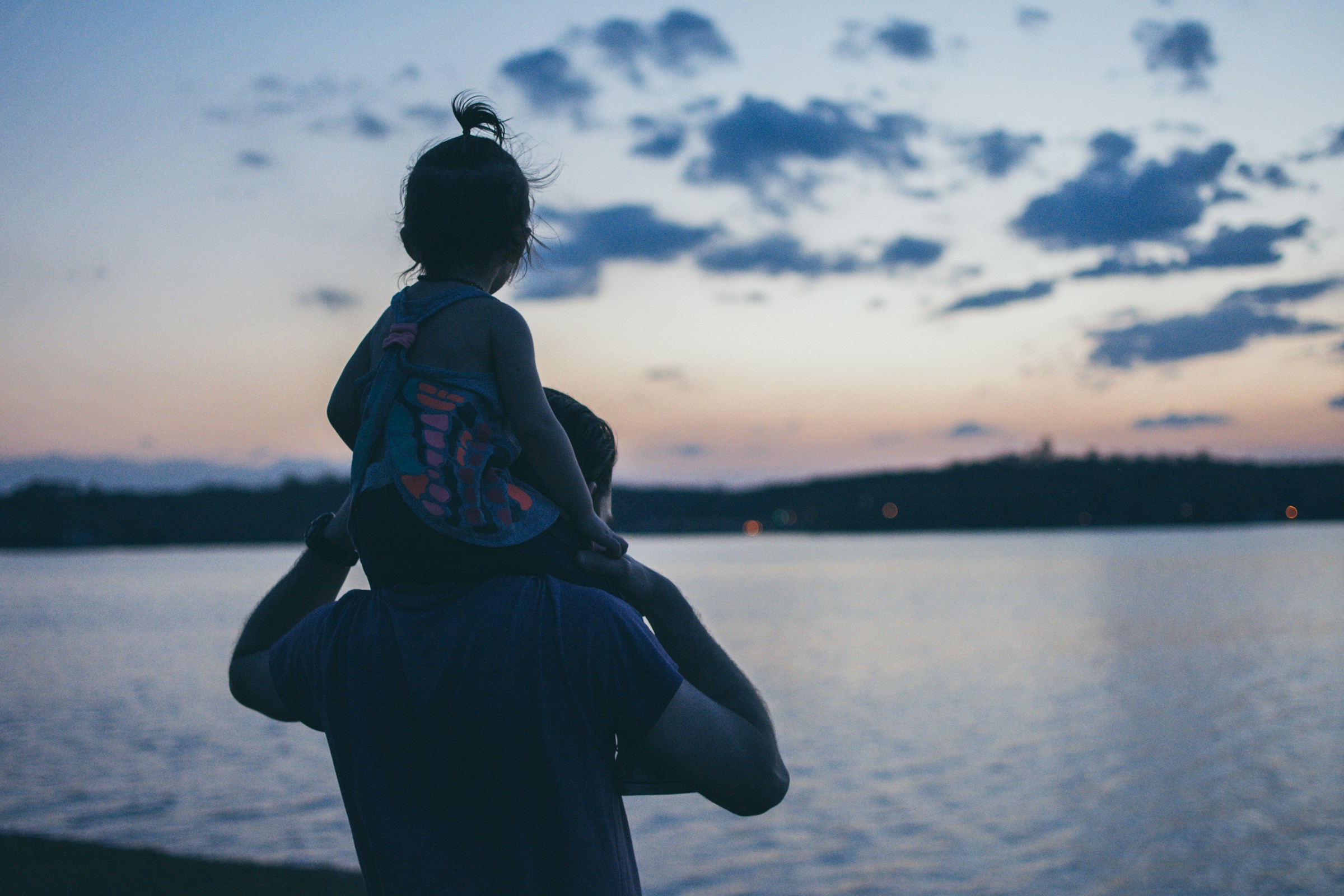 Man carrying daughter and looking at water | Source: Unsplash