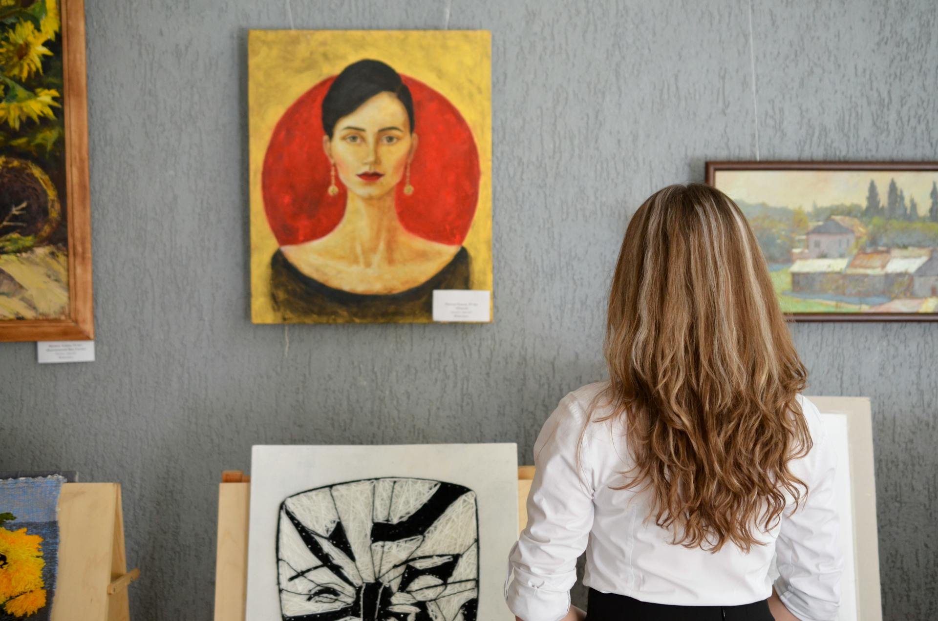 A young woman looking at paintings displayed on a wall | Source: Pexels