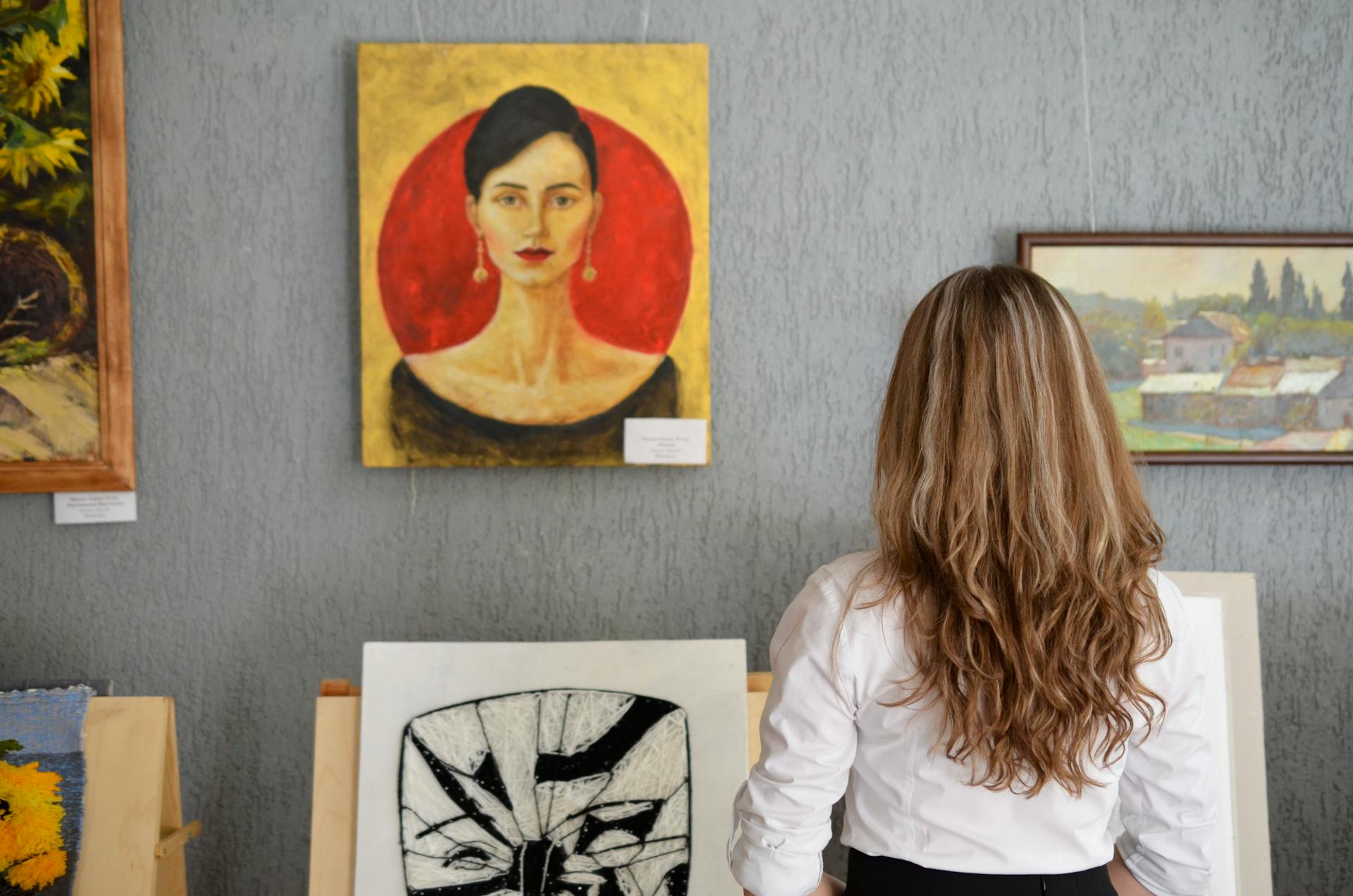 A back view of a woman looking at a painting displayed on a wall | Source: Pexels