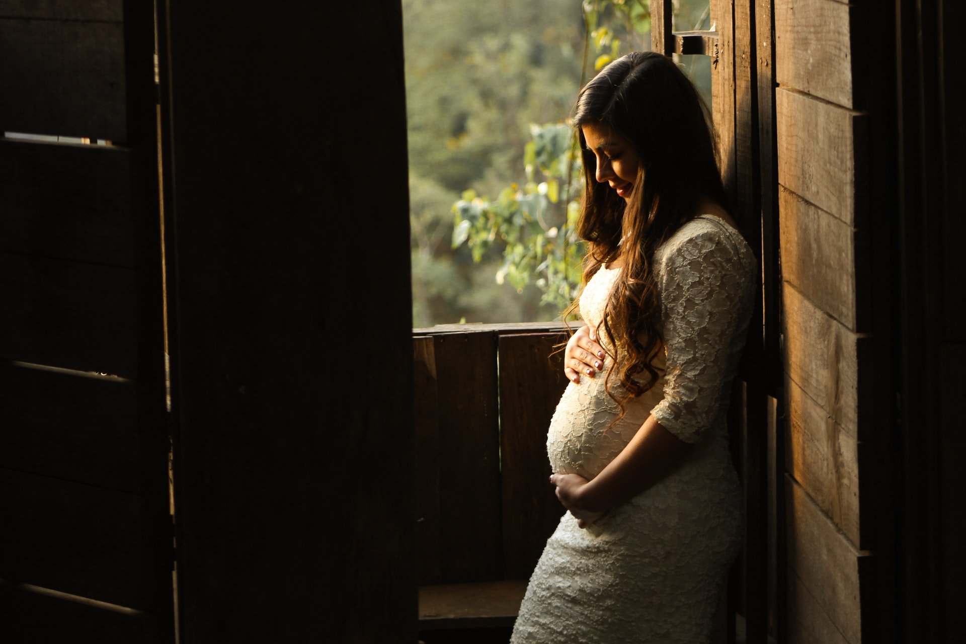 A pregnant woman holding her belly while leaning on a wall | Source: Unsplash