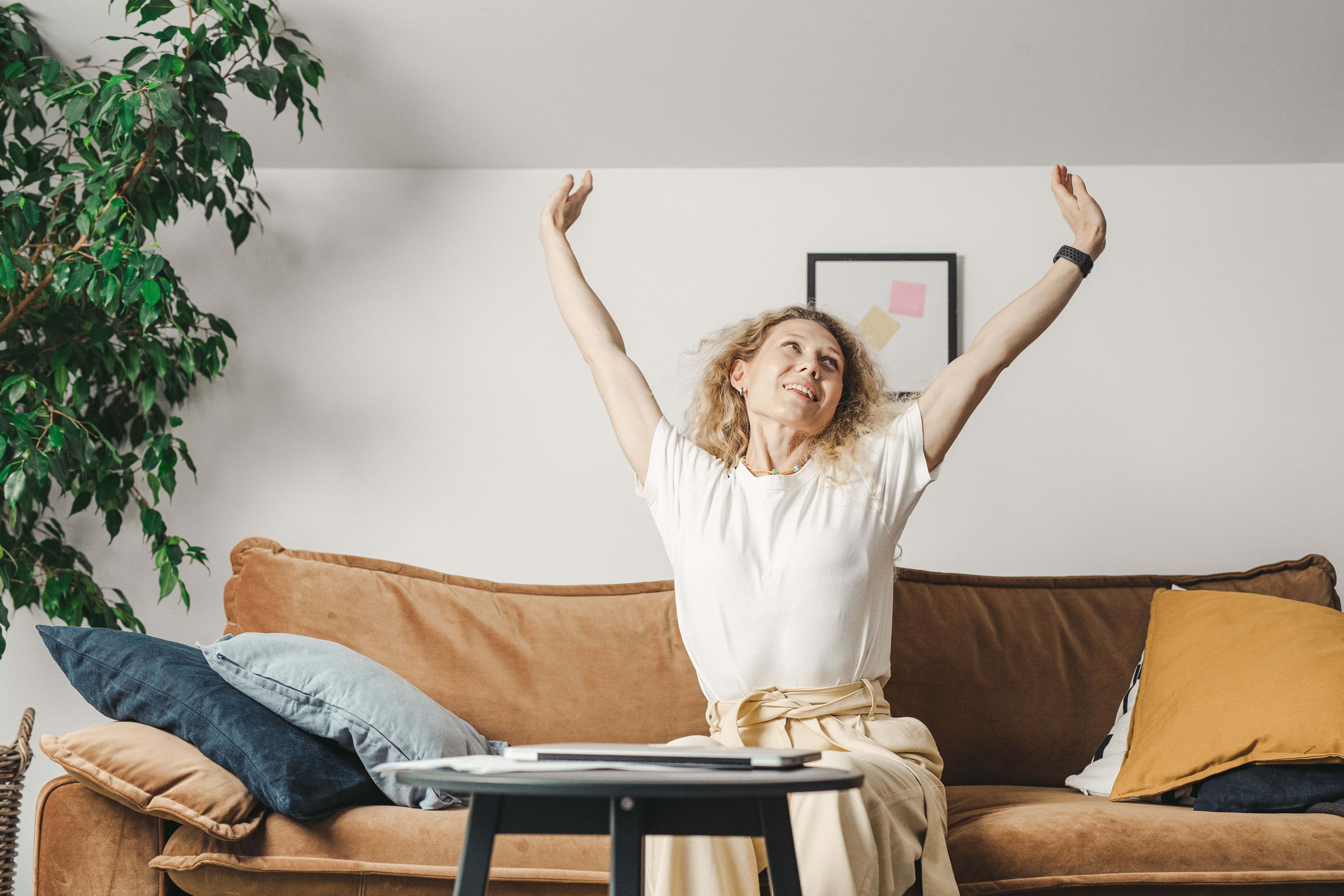 Woman stretching her arms out in glee while seated on a couch | Source: Pexels