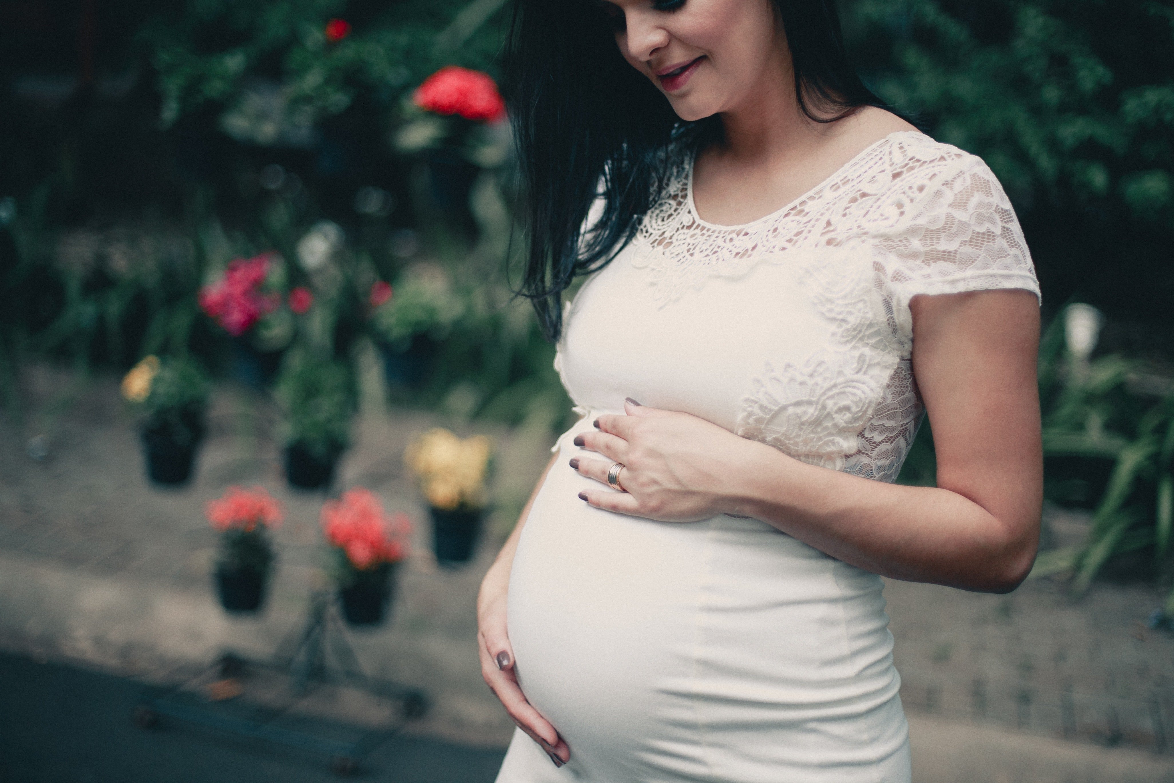 Mujer embarazada rodeada de naturaleza sosteniendo su panza. | Foto: Pexels