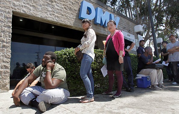 A man sits on the floor as he joined people in a line outside the DMV office, on Tuesday, Aug. 14, 2012, Los Angeles Source: Luis Sinco/Los Angeles Times via Getty Images
