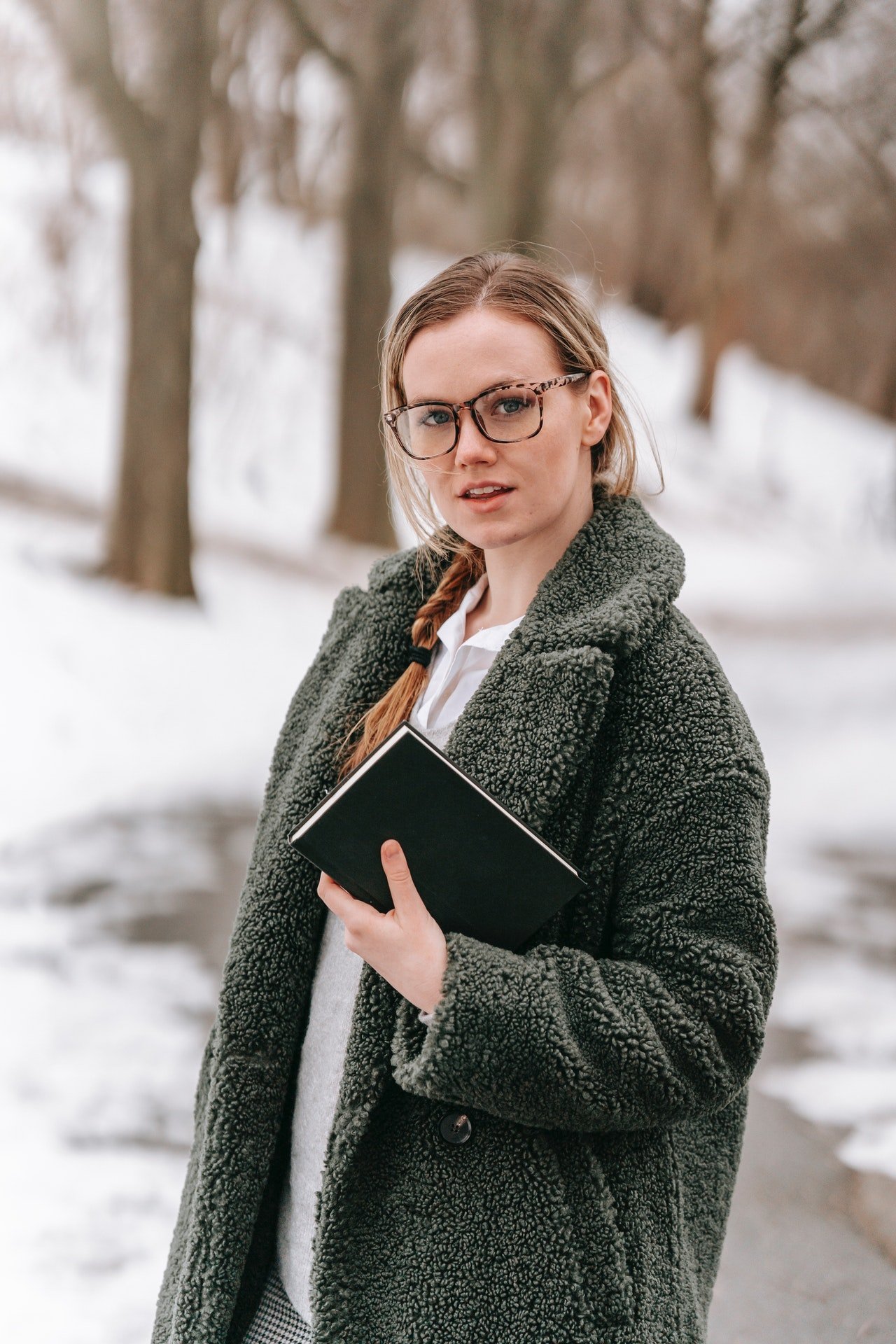 Una mujer con anteojos sosteniendo un libro. | Foto: Pexels