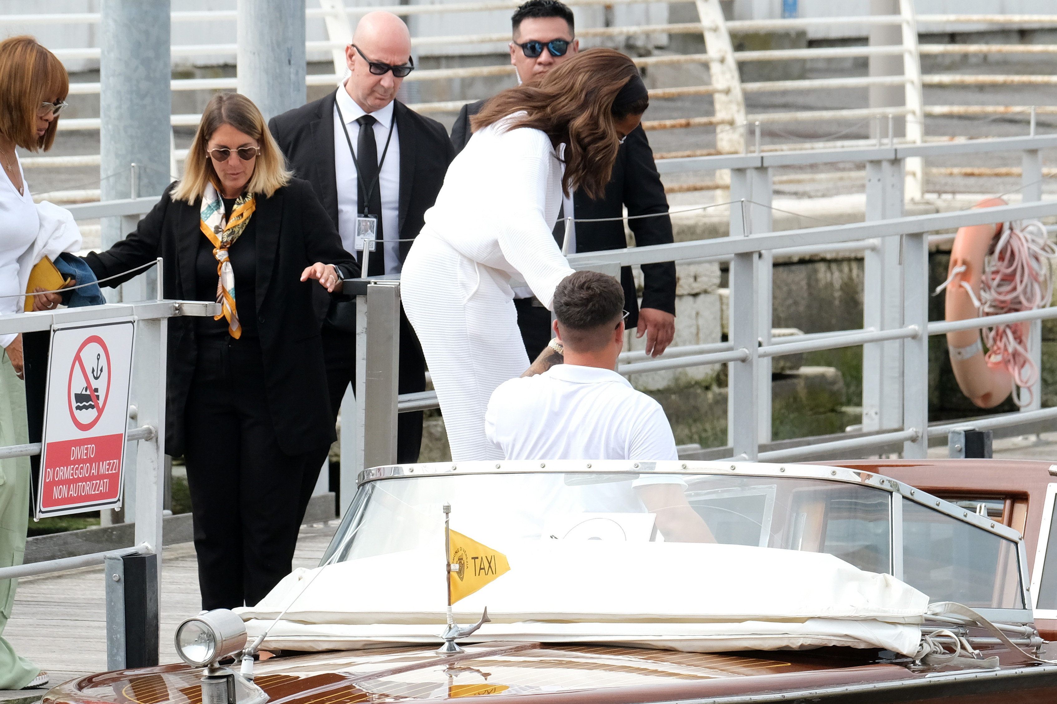 Oprah Winfrey is at the Marco Polo airport in Venice. She steps into the taxi boat with the help of the taxi boat guide.