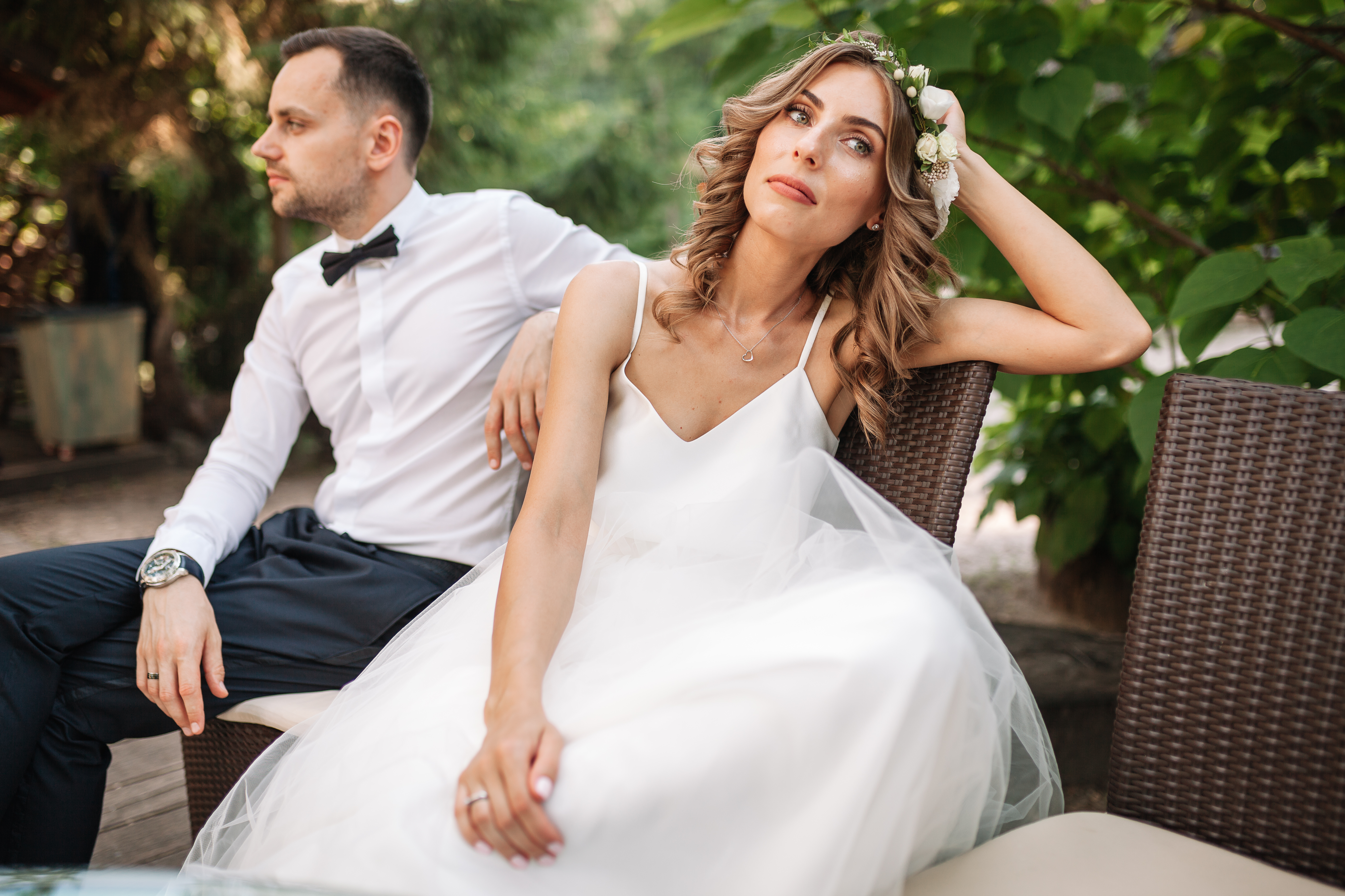A bride and groom seated at a bench, both looking away from each other | Source: Shutterstock