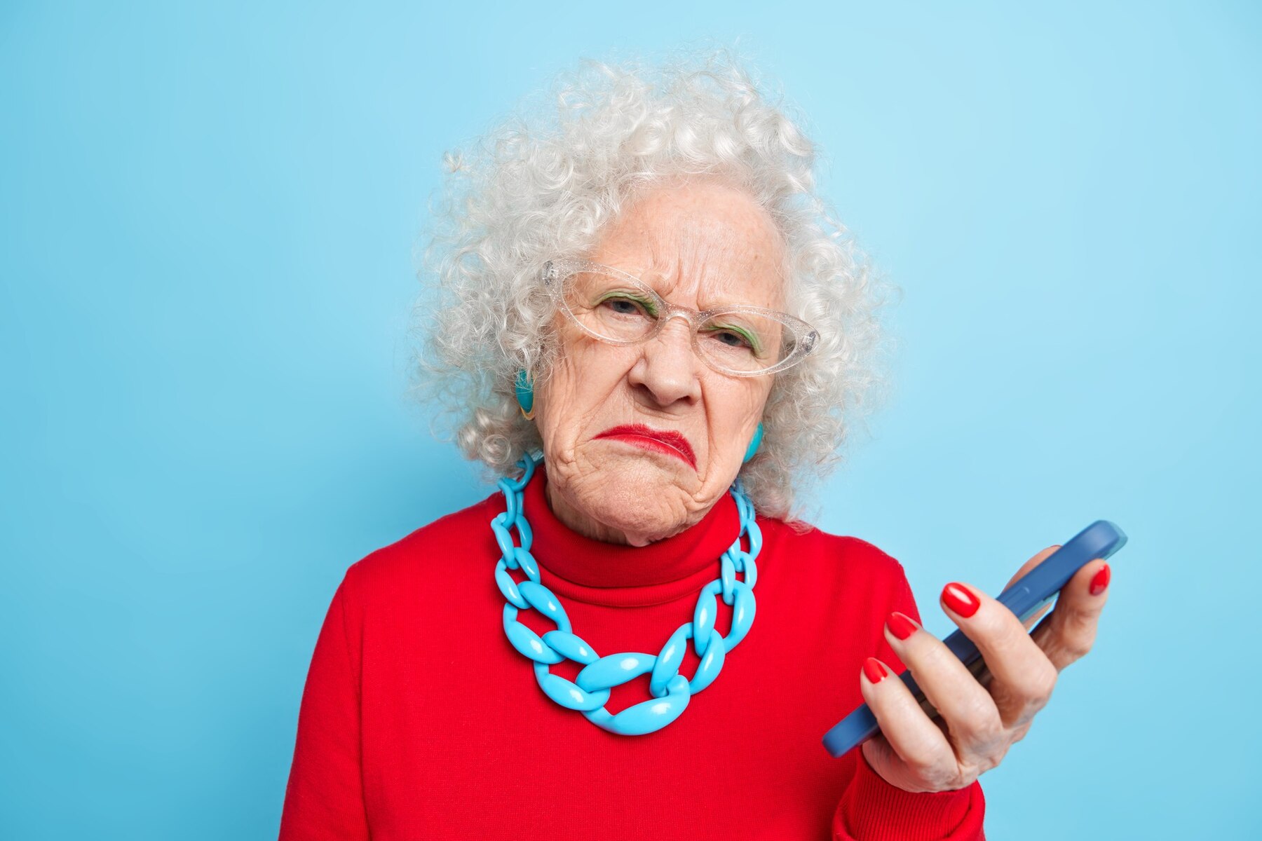 An angry elderly woman holding a phone | Source: Freepik