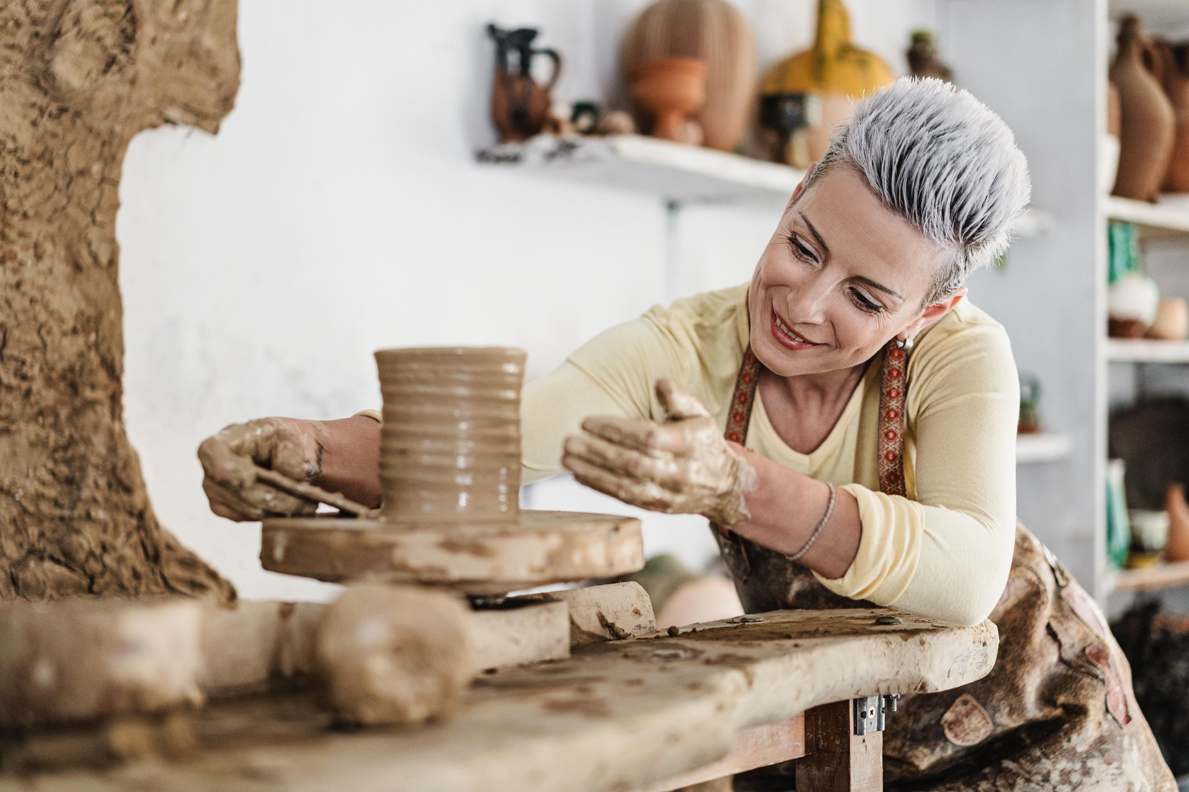women, making clay pottery on a pottery wheel in the art studio | Source: Getty Images