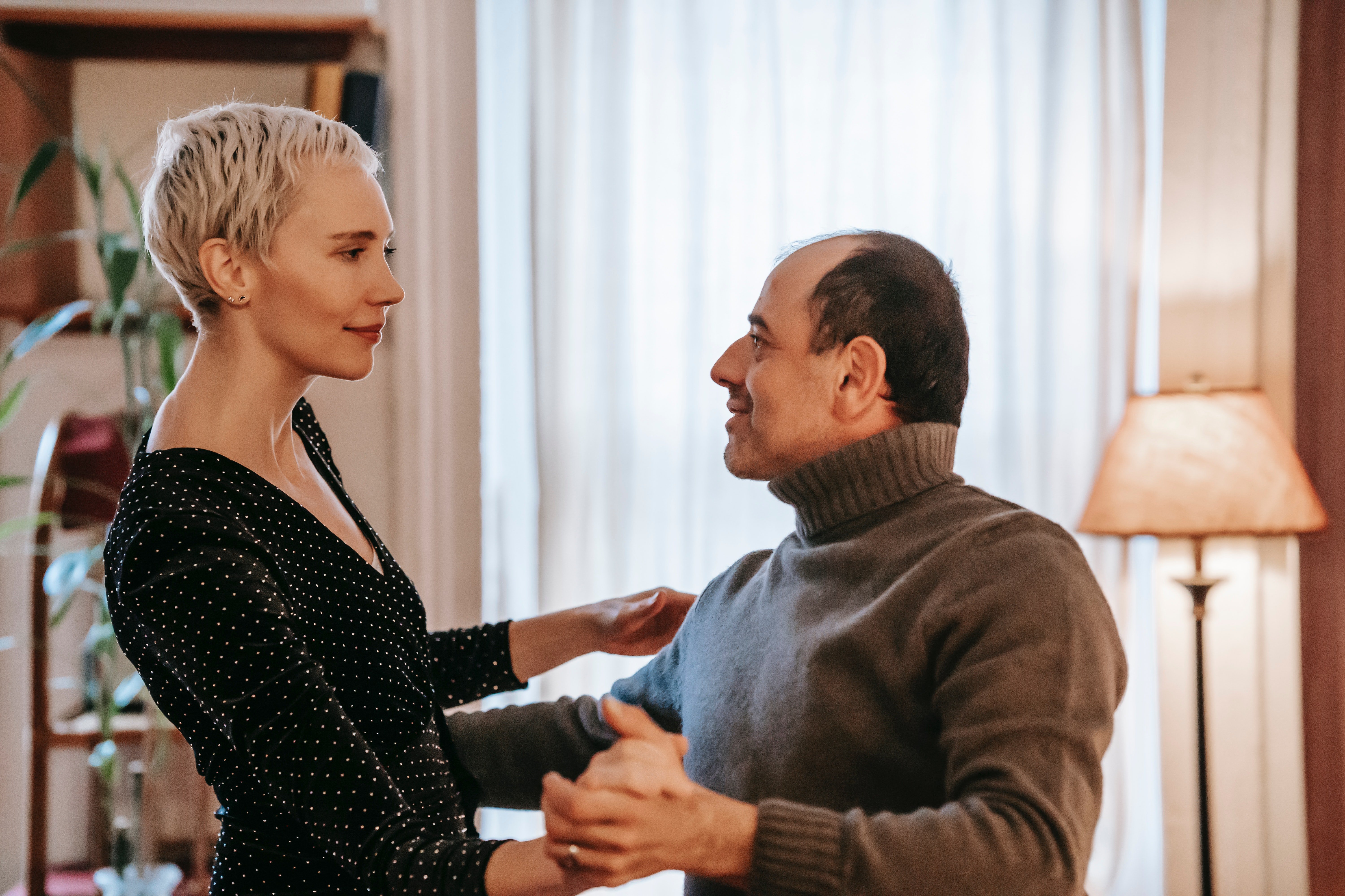 A man and a woman looking at each other as they dance. | Pexels/ Gary Barnes