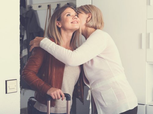 Madre e hija que sale con una maleta comparten un abrazo. | Foto: Shutterstock
