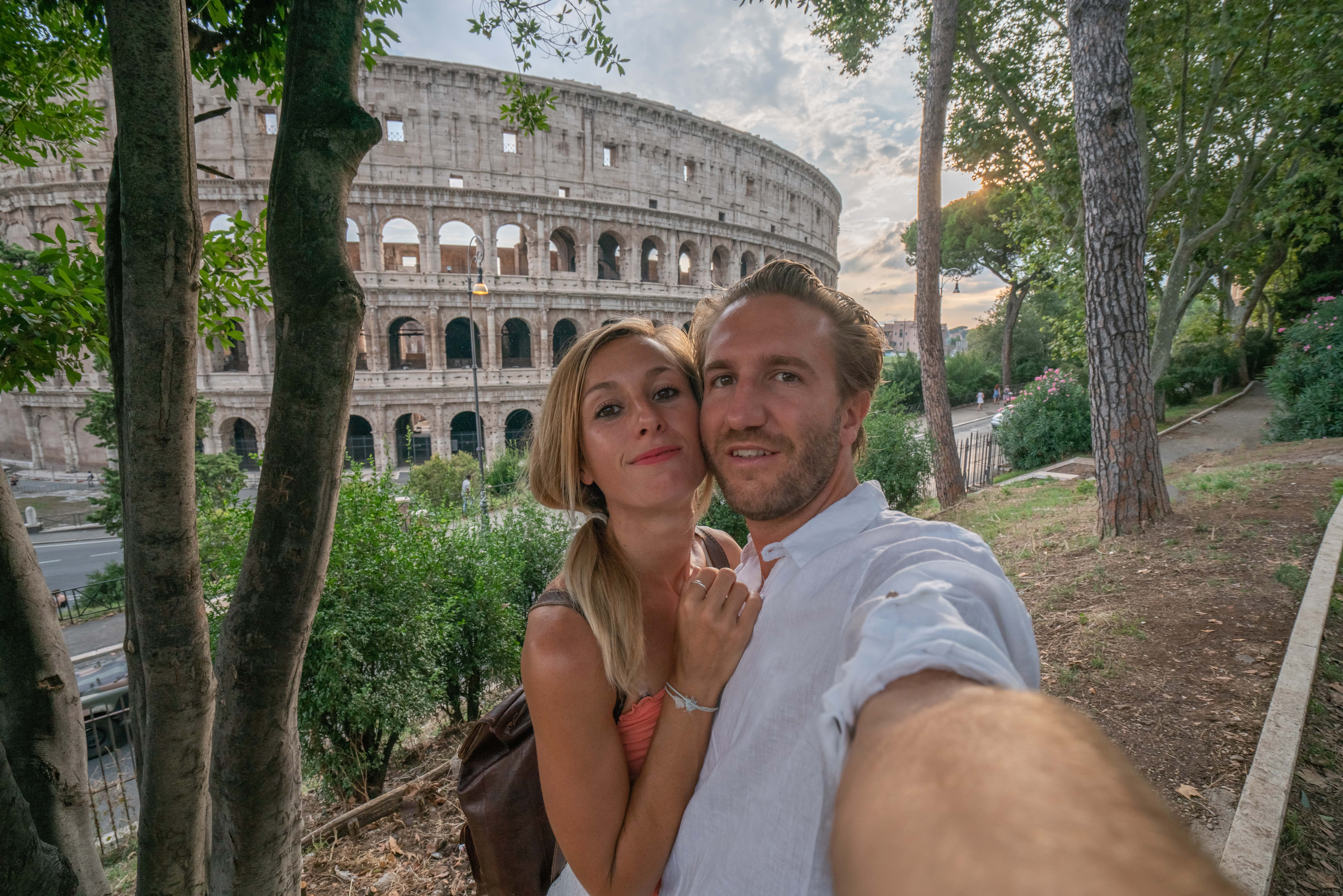 A couple posing for a selfie in front of the Colosseum in Rome | Source: Getty Images