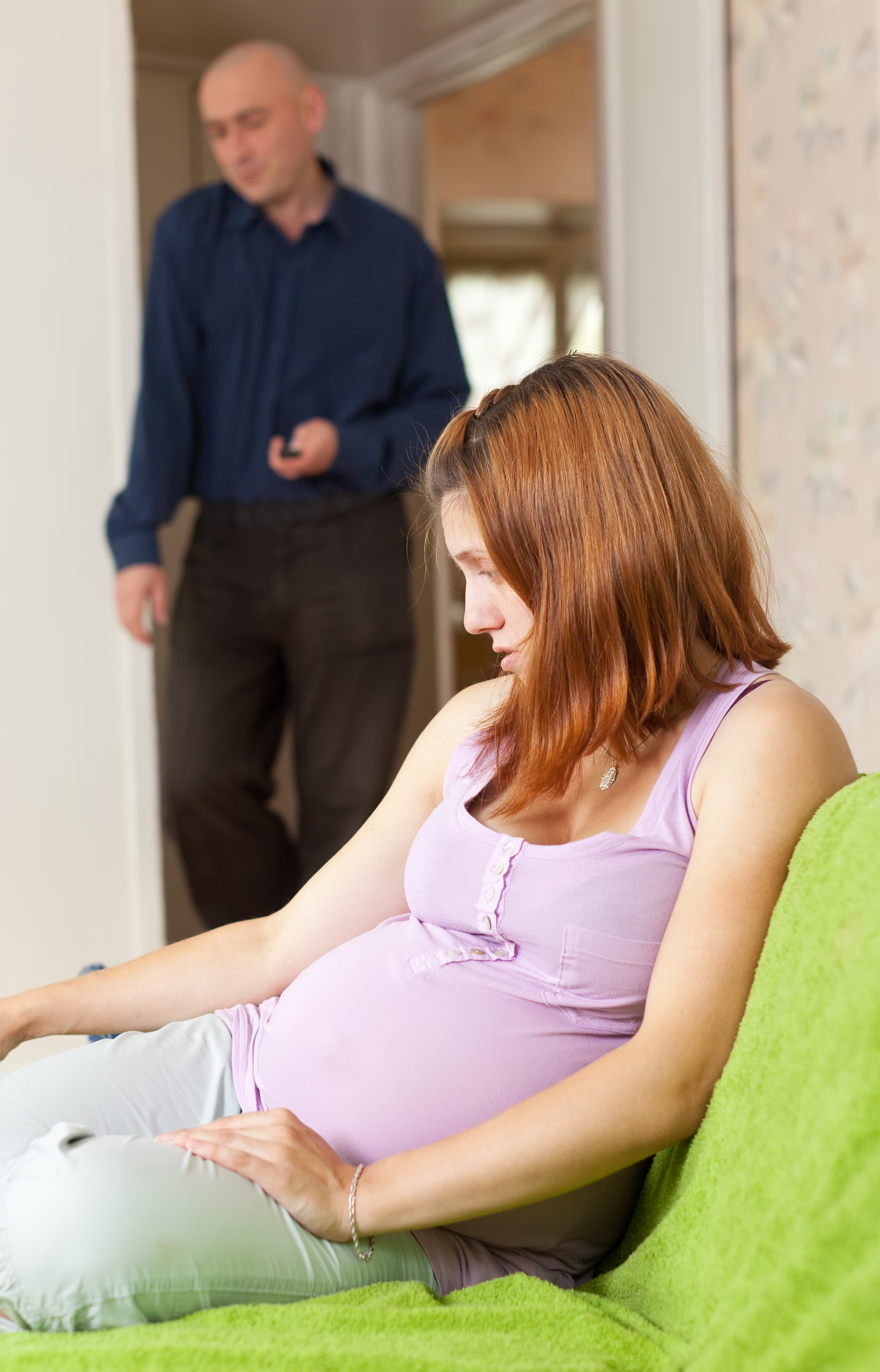 A pregnant woman looking down as a man looks away in the background | Source: Shutterstock