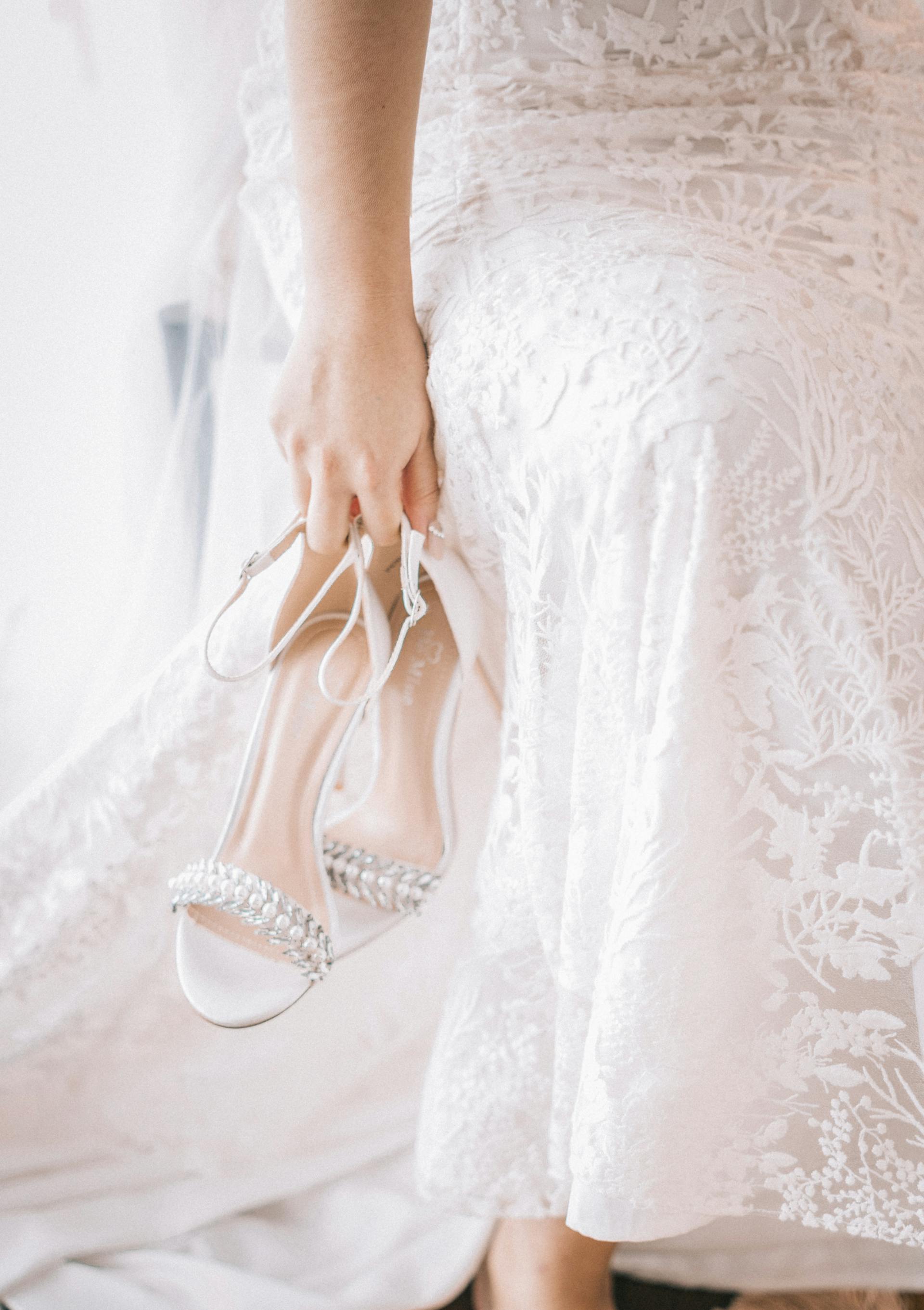A woman in a white dress carrying shoes | Source: Pexels