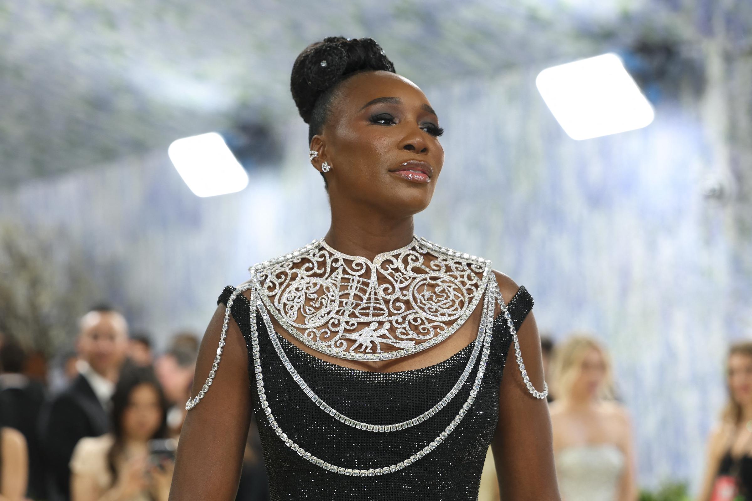 Venus Williams arrives in New York wearing a glittering black gown, her sculptural updo and silver collar catching the lights as cameras flash around her.