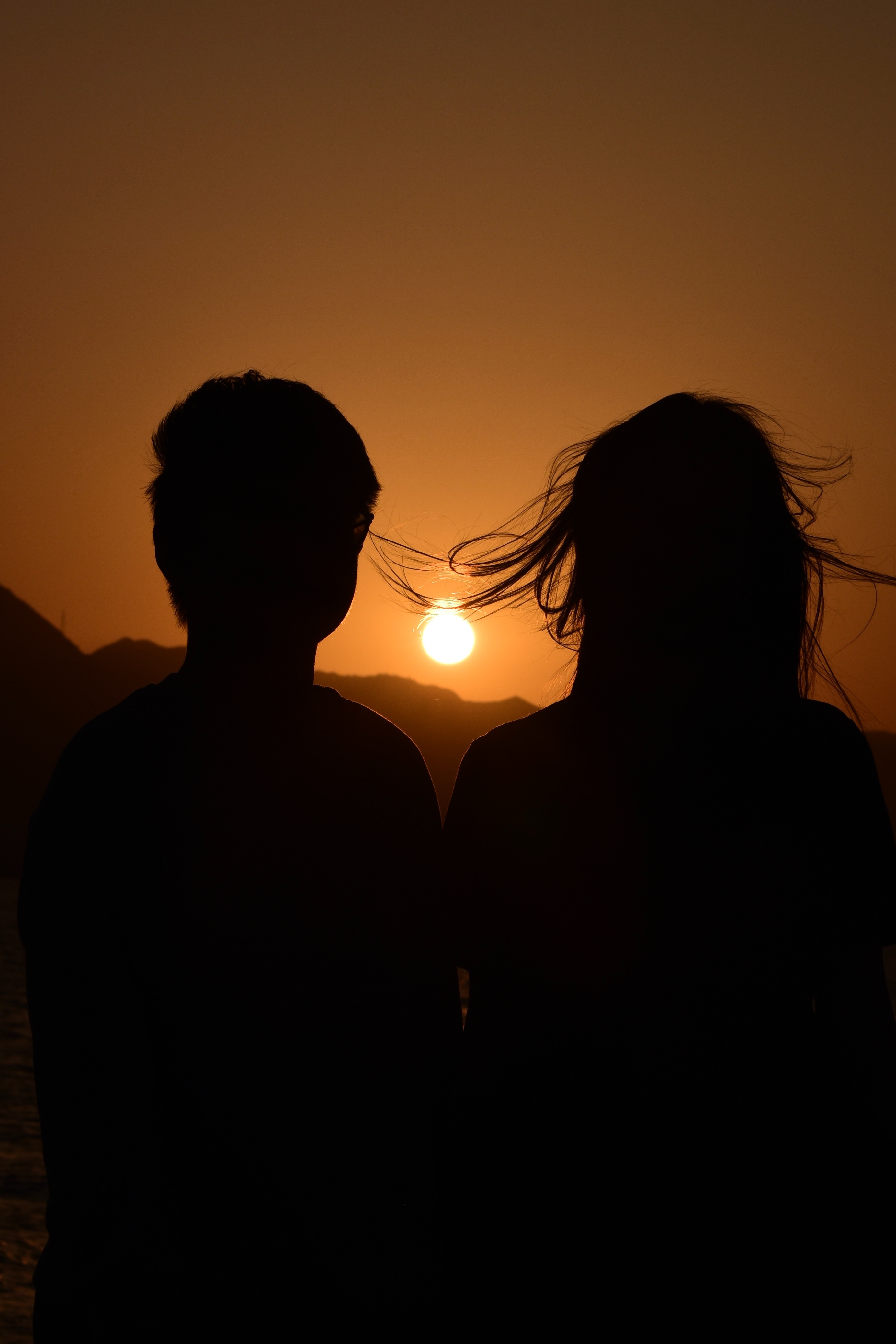 A couple in front of a sunset. | Source: Pexels