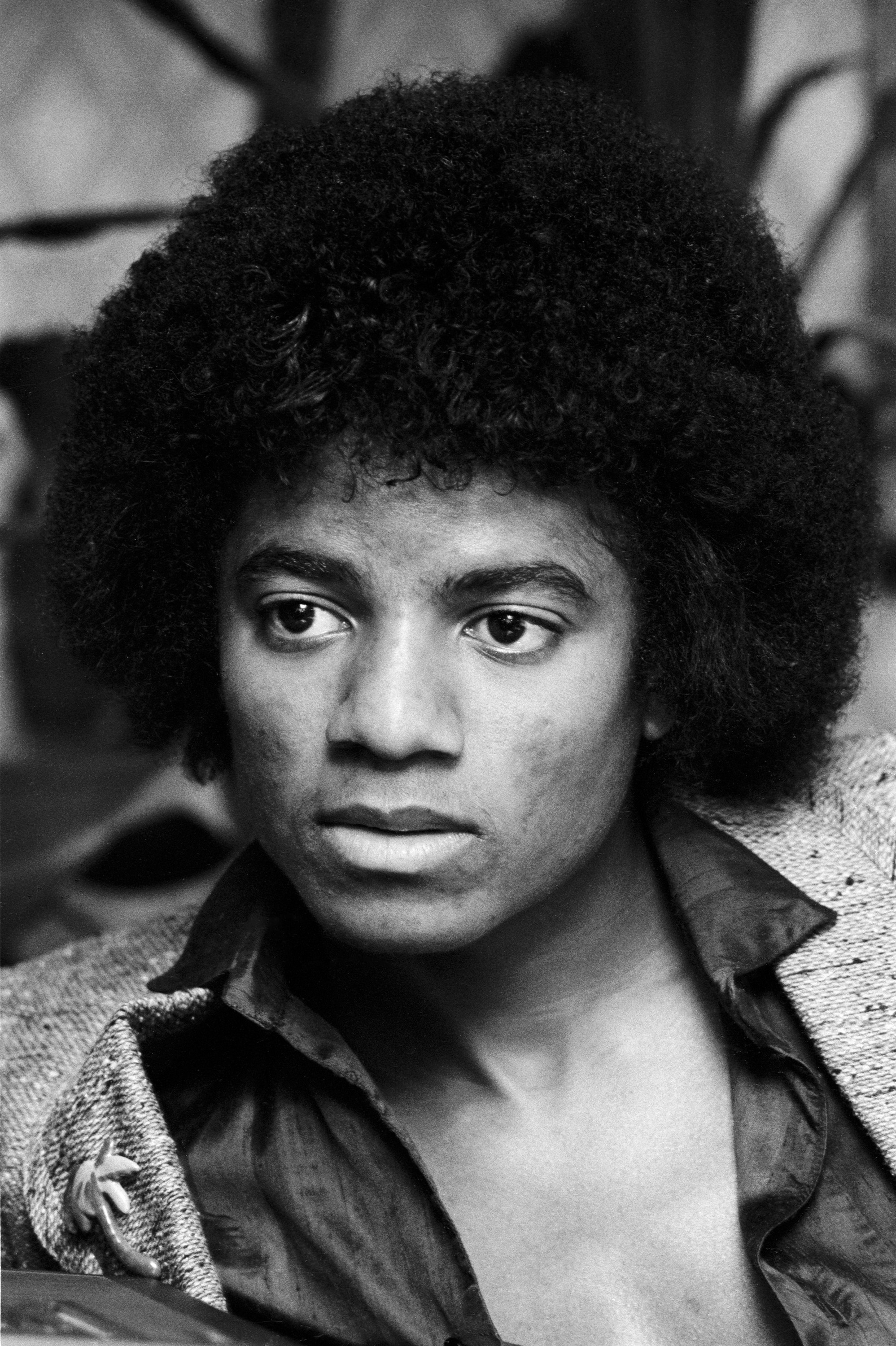 Michael Jackson dresses in an open-collar shirt and textured jacket. | Source: Getty Images