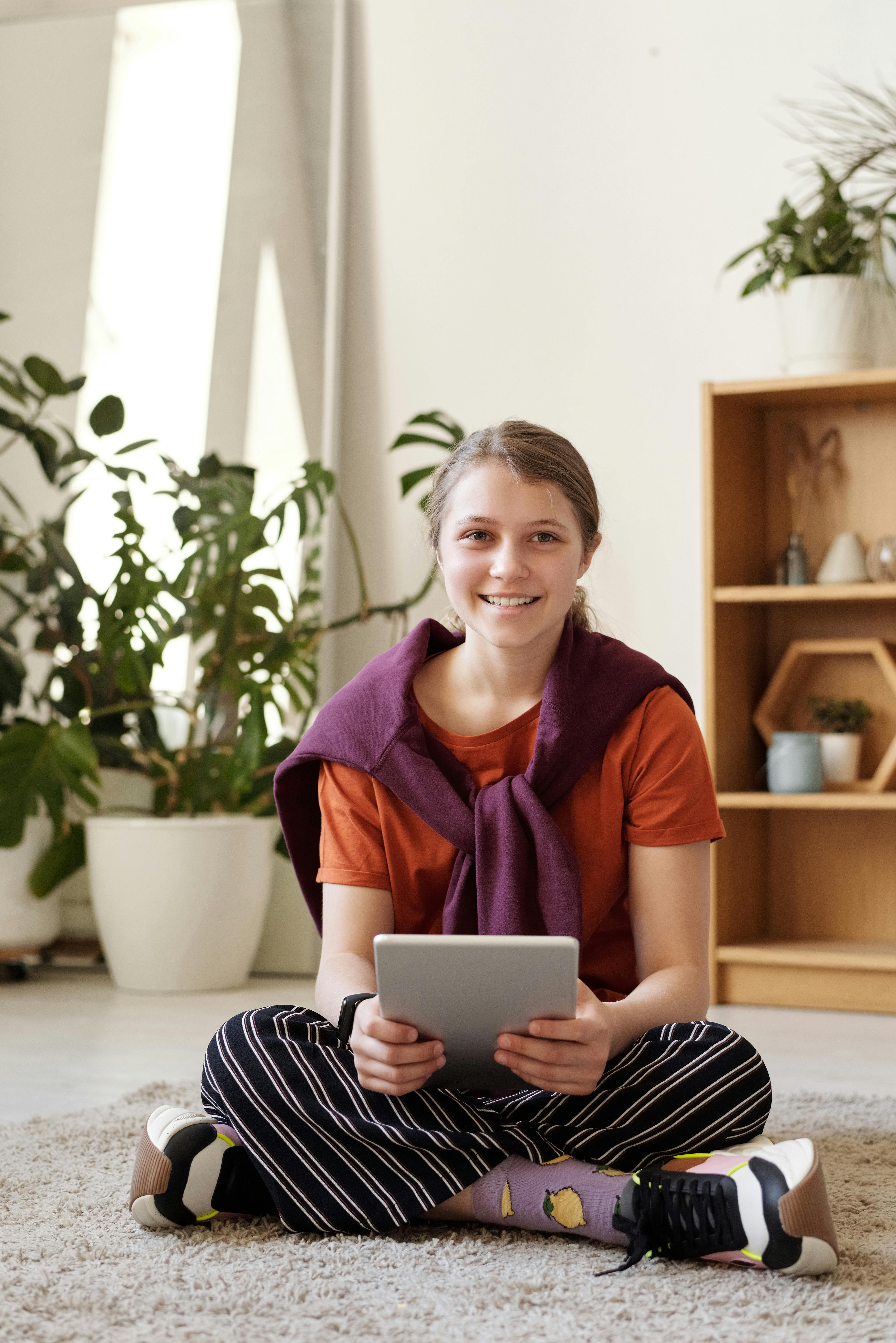 A happy girl sitting on the floor | Source: Pexels