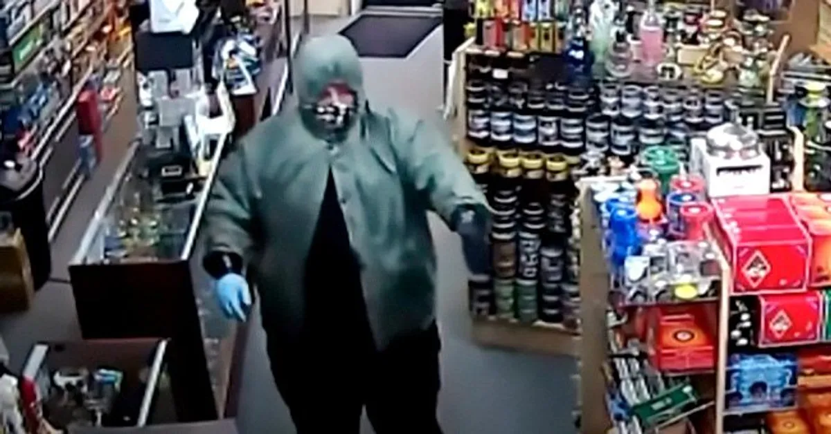 Disguised man holding up a gun in a store.┃Source: youtube.com/WNCNTV