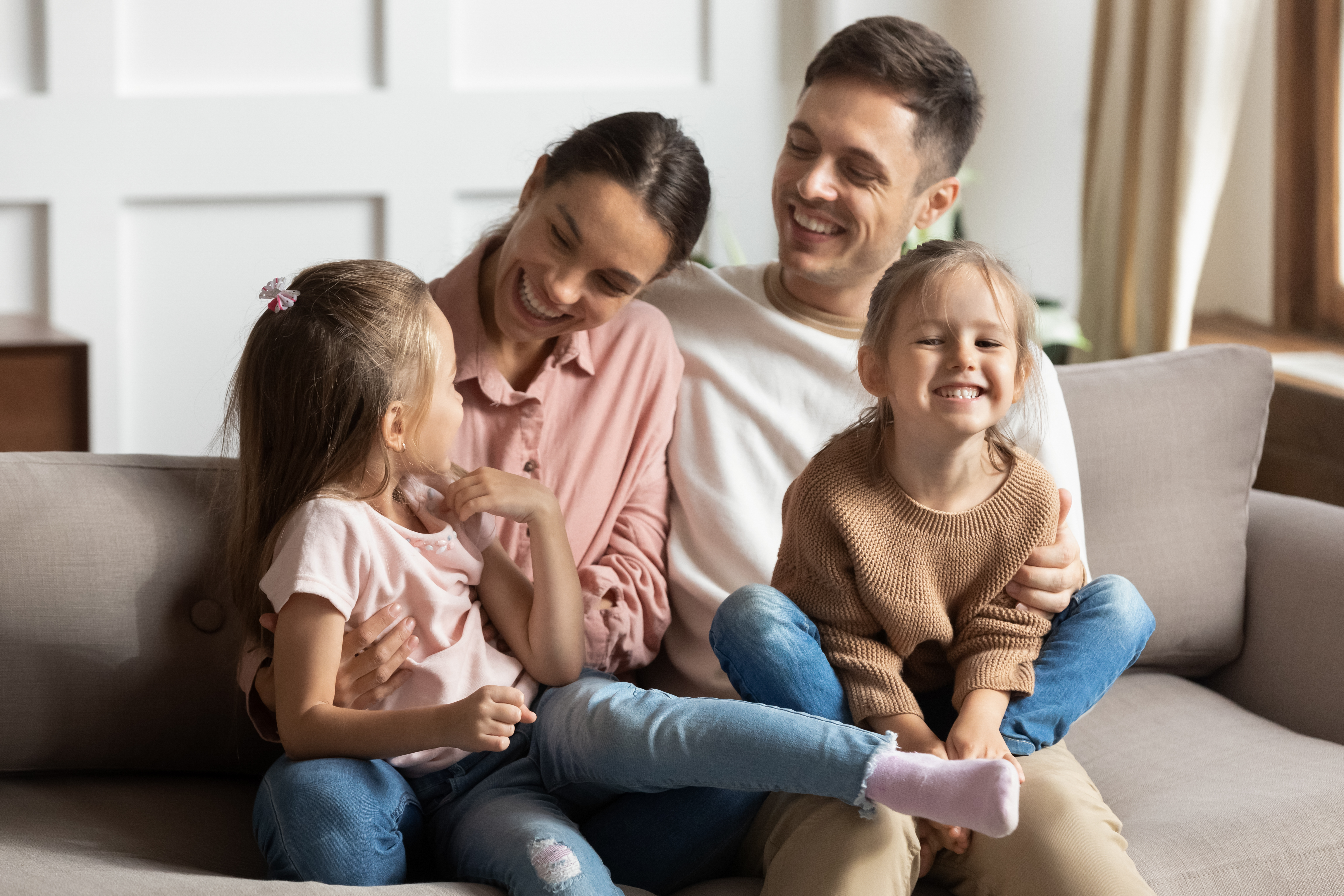 Smiling parents having a sweet family moment with their daughters | Source: Shutterstock