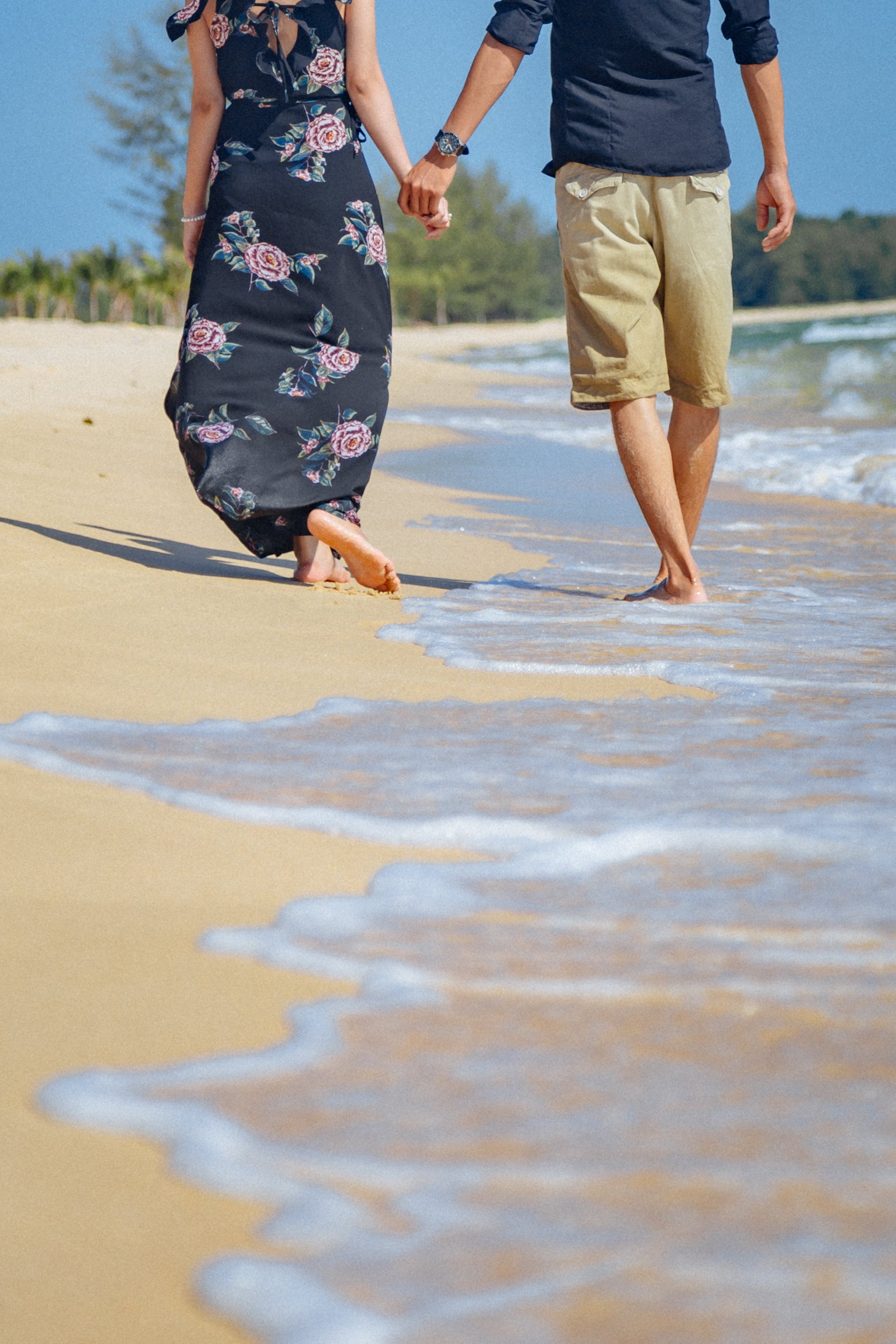 A couple holding hands while strolling on the beach. | Source: Pexels