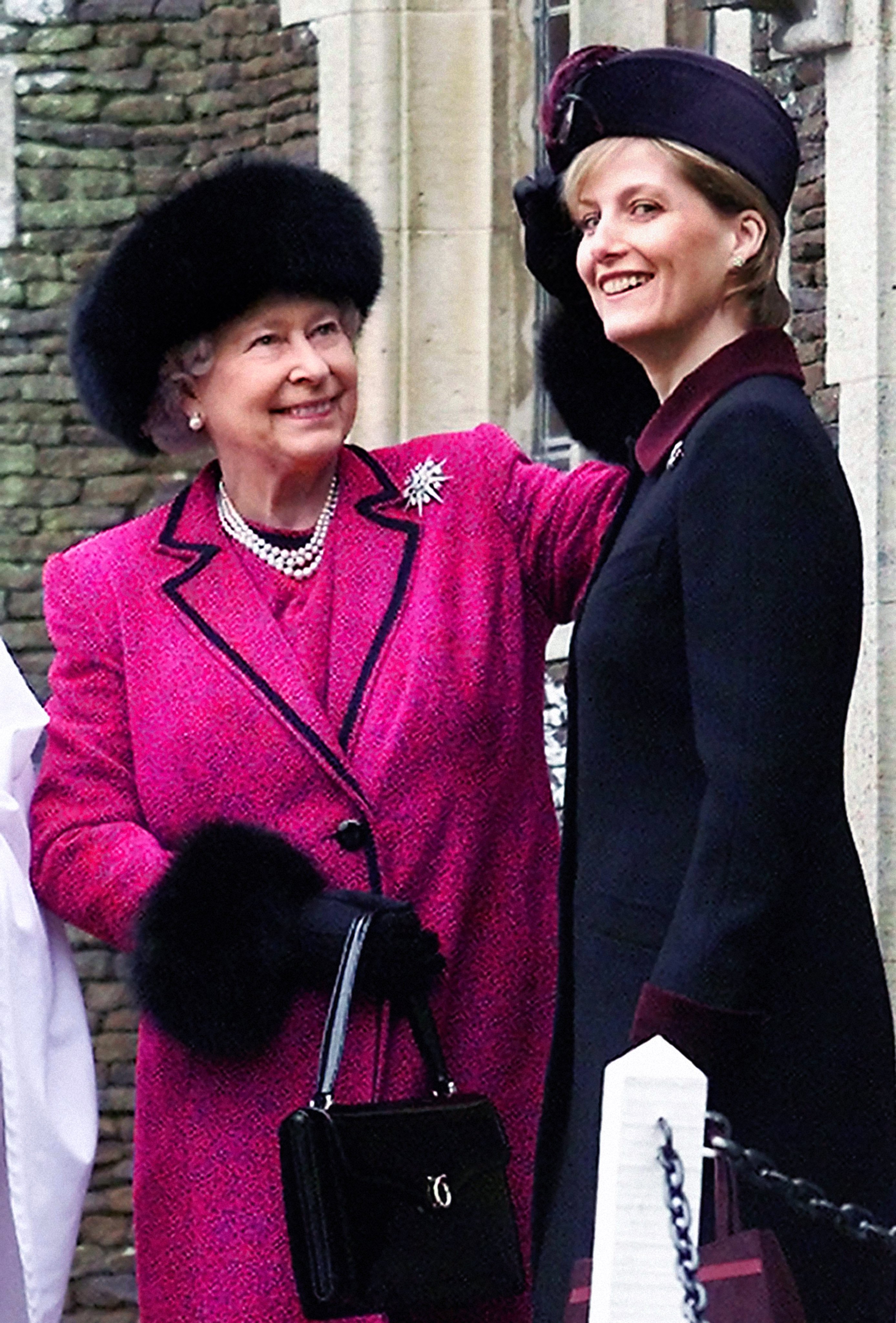 Queen Elizabeth II straightens Sophie, The Countess of Wessex's hat, while they wait to attend the Christmas Day service at the Sandringham Church, December 25, 2002  | Source: Getty Images