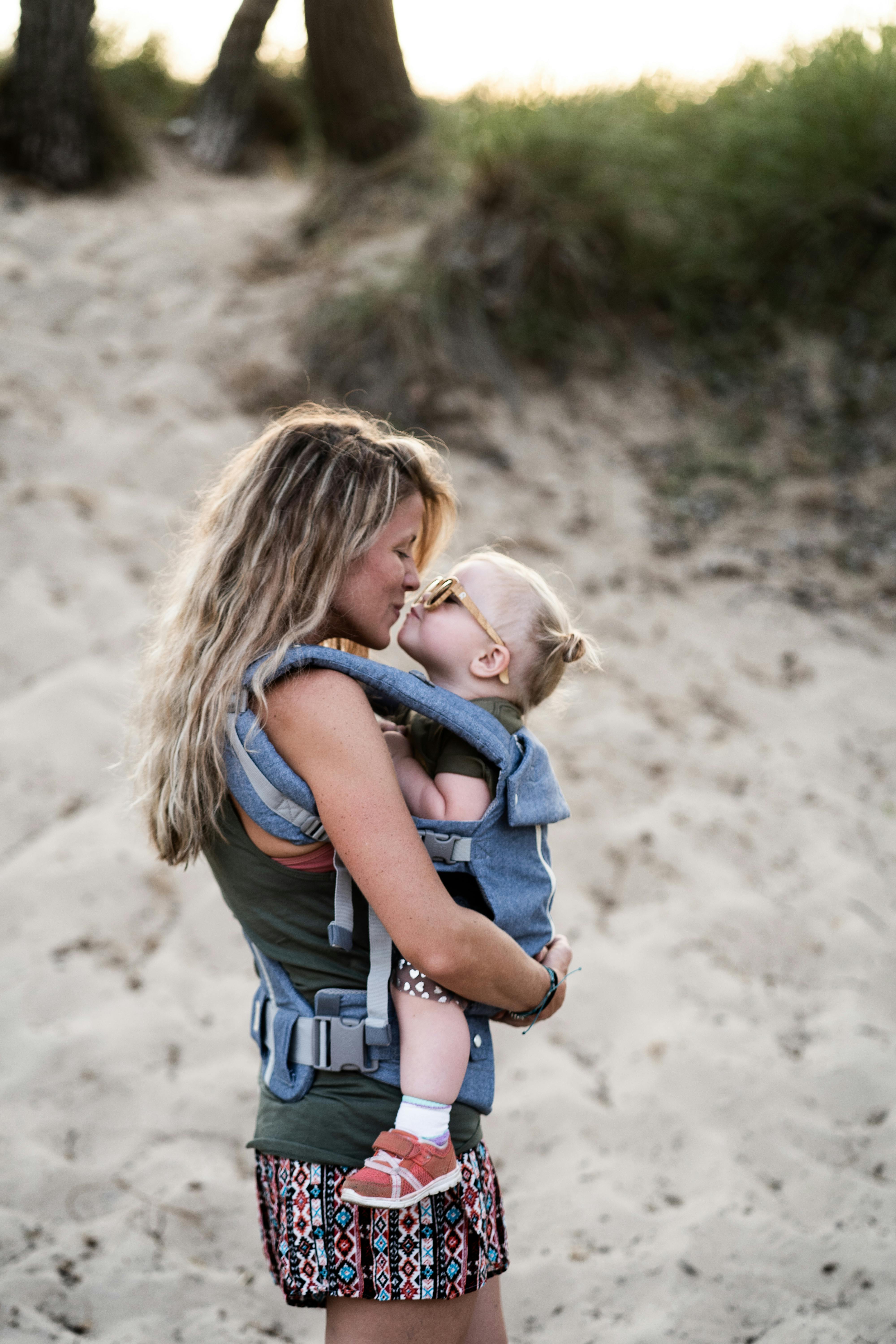 A woman about to share a kiss with a toddler at the beach | Source: Pexels