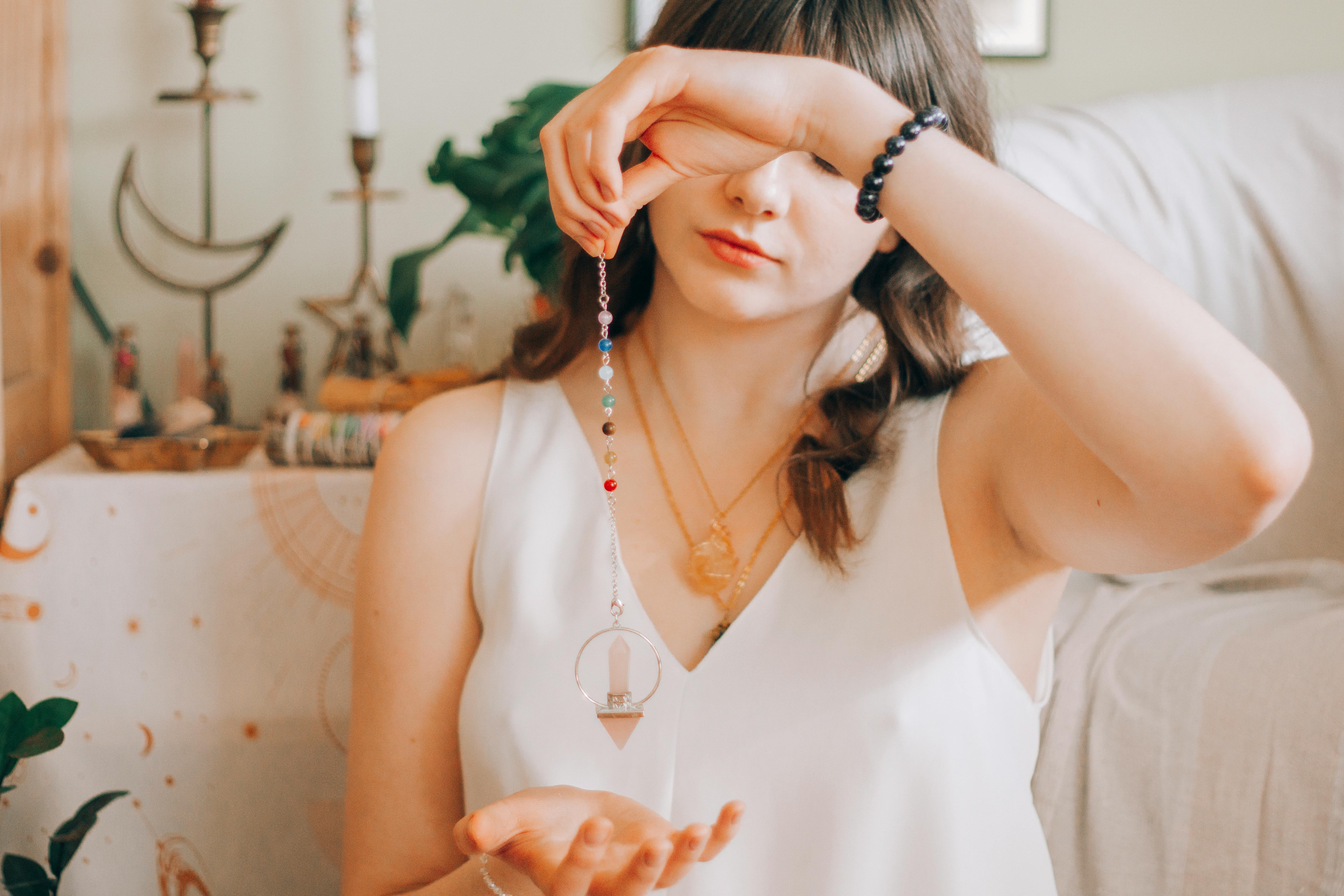 A woman holding a pendulum over her palm | Source: Pexels