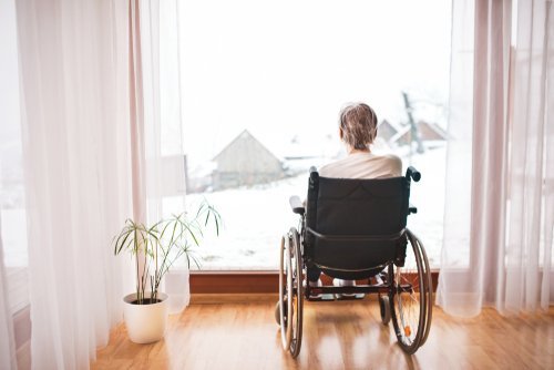 A woman in a wheelchair looking out a window. | Source: Shutterstock.