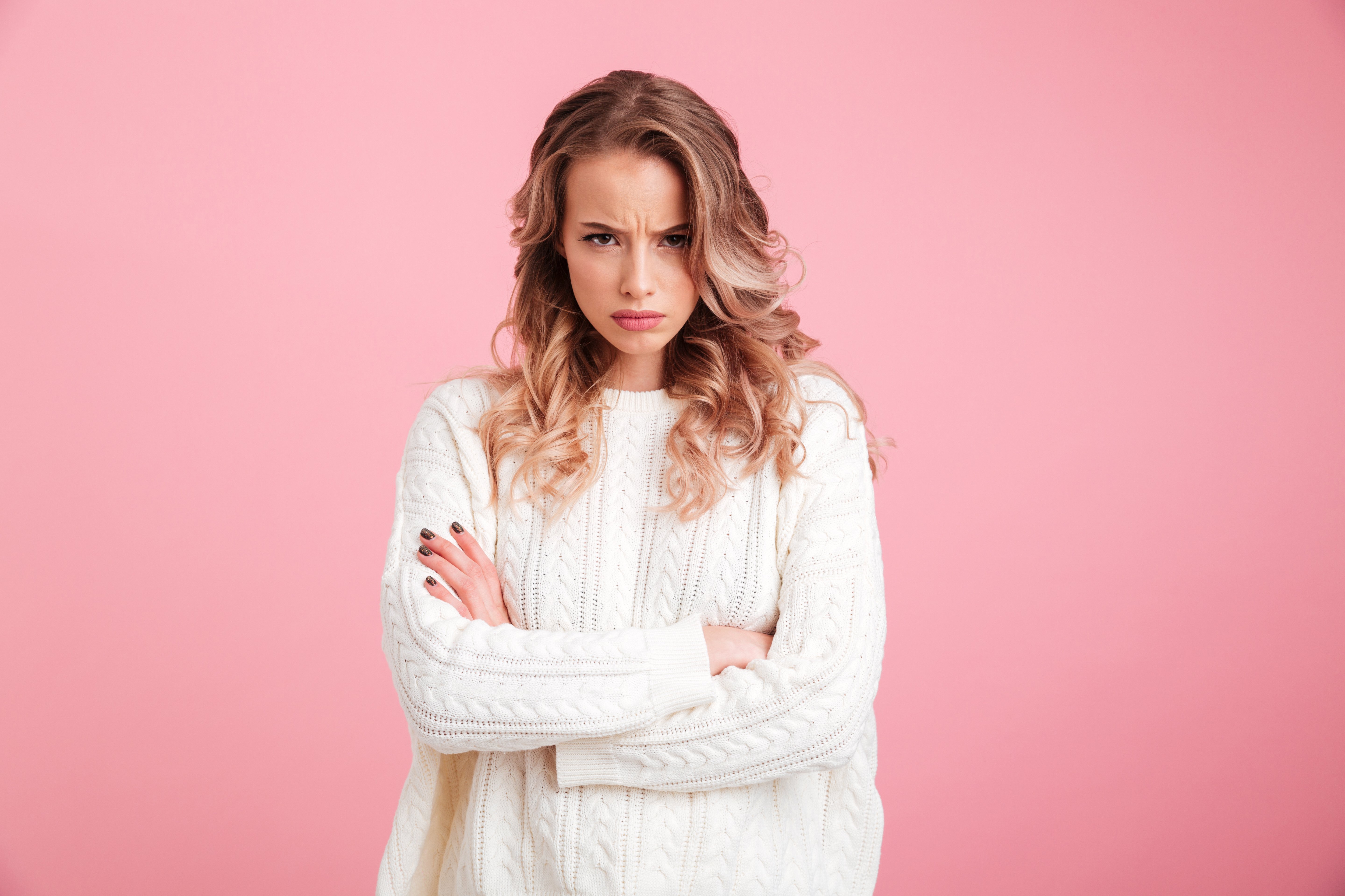 Bild der verärgerten jungen Frau, die vor rosa Hintergrund steht | Quelle: Shutterstock