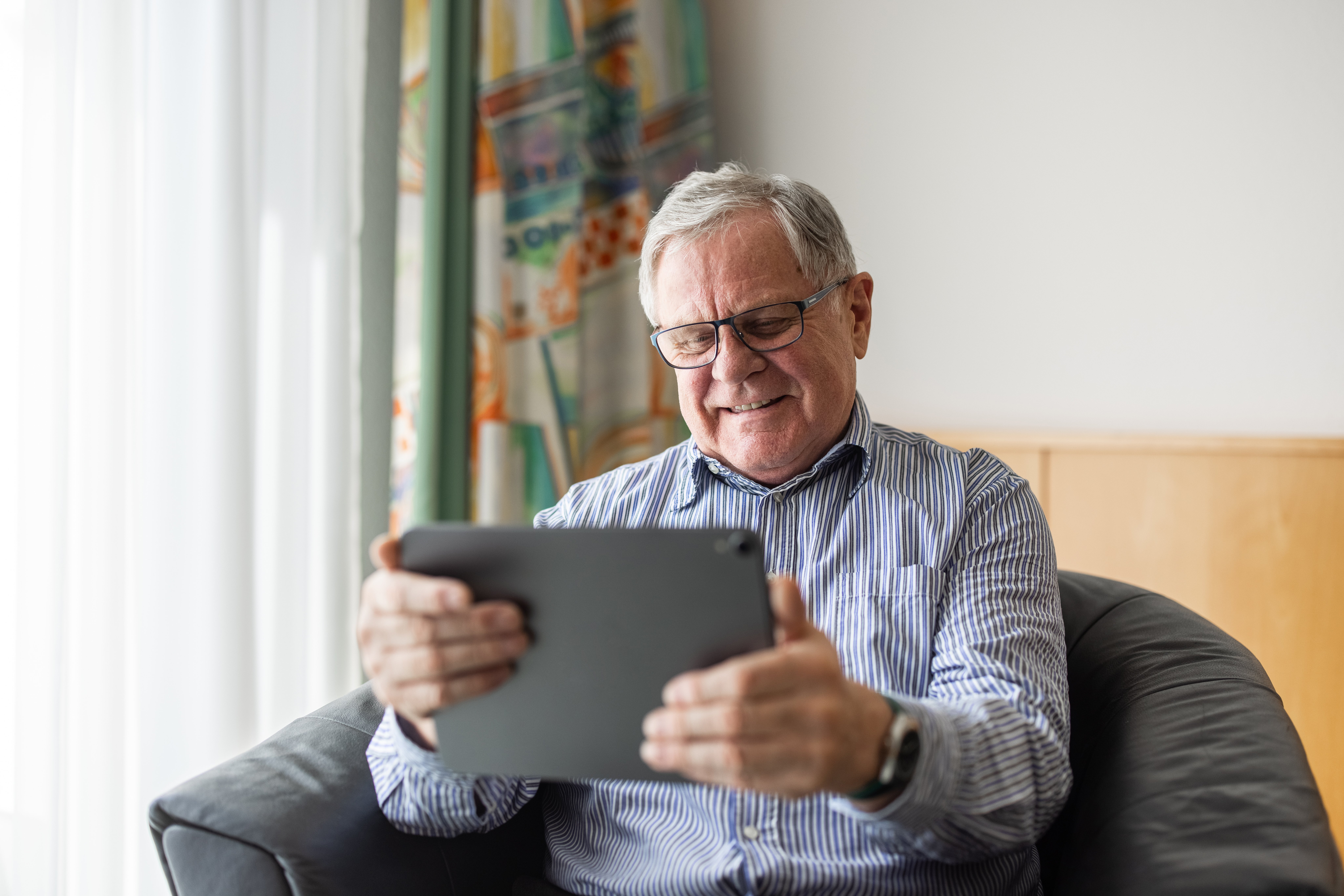 An old man sitting at home and using a digital tablet for video calling | Source: Getty Images